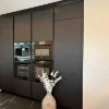 Eine moderne schwarze Einbauküche mit einem Strauß weißer Blumen, Nolte Küchen.