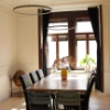 Salle à manger avec longue table en bois, chaises et lampes modernes, assorties à Nolte Living.