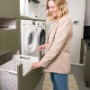 Une femme se tient dans une buanderie moderne avec lave-linge et sèche-linge de Nolte Utility Rooms.