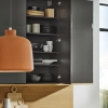 Une cuisine moderne avec armoire ouverte montrant vaisselle et accessoires en bois, Nolte Kitchen.
