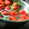 Des fraises flottent dans un bol en métal rempli d'eau.