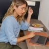 A woman working on a laptop in a modern kitchen. Nolte Kitchens.