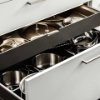 Ein geöffneter Küchenschrank zeigt Töpfe und Pfannen in einem modernen Design von Nolte Küchen.
