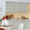 In einer modernen Küche mit grauen Schränken und Holzdetails steht ein Tisch mit Blumen. Nolte Küchen.