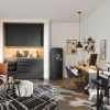 A modern room with a gray Nolte kitchen features a sofa, desk, and electronic drum set.