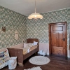 Une chambre d'enfant avec un lit en bois, du papier peint à fleurs et un tapis rond sur un sol en bois.