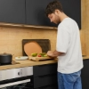 Un homme prépare des ingrédients dans une cuisine moderne, entouré de cuisines Nolte.