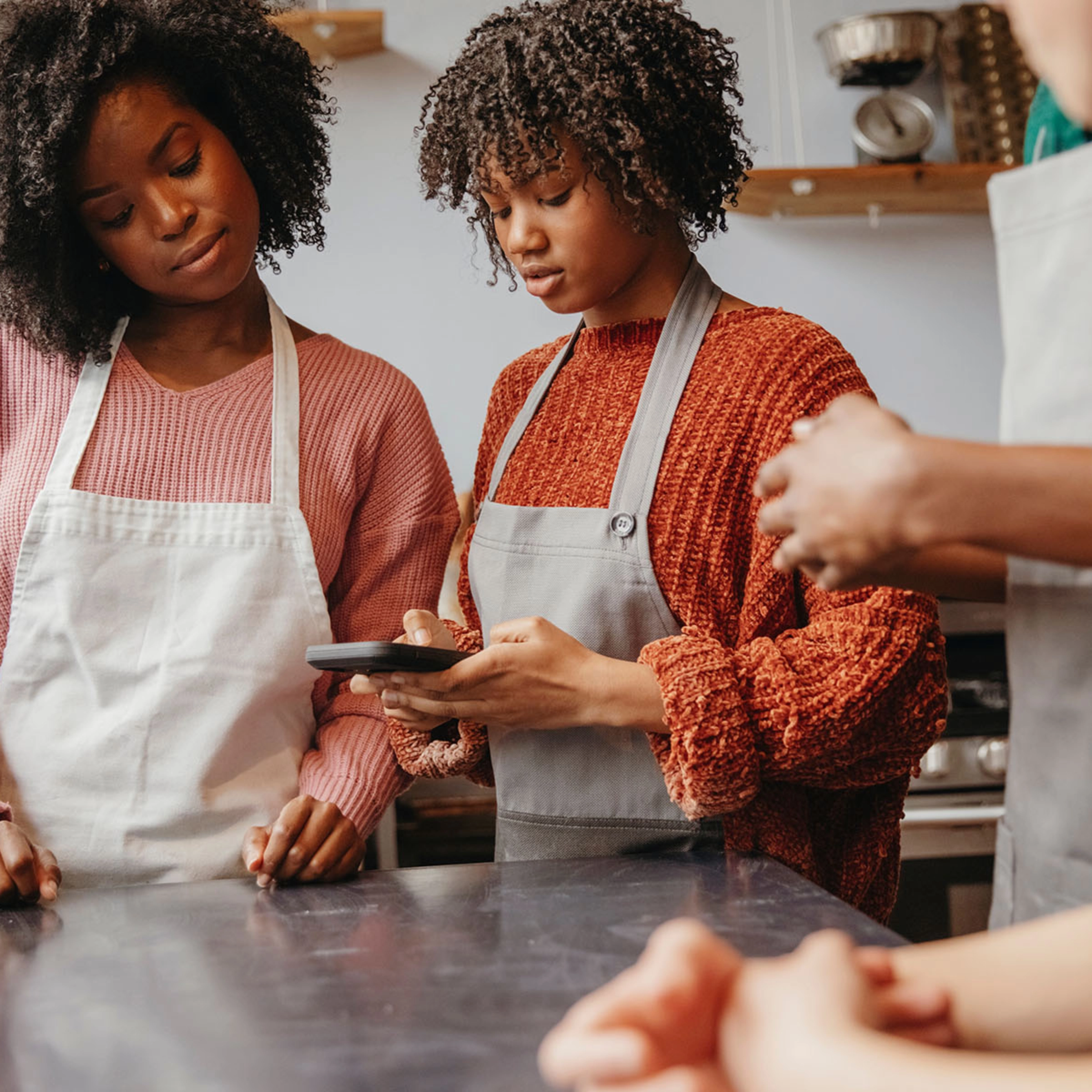 Twee mensen met schorten gebruiken een tablet in een moderne keuken, Nolte Kitchen.