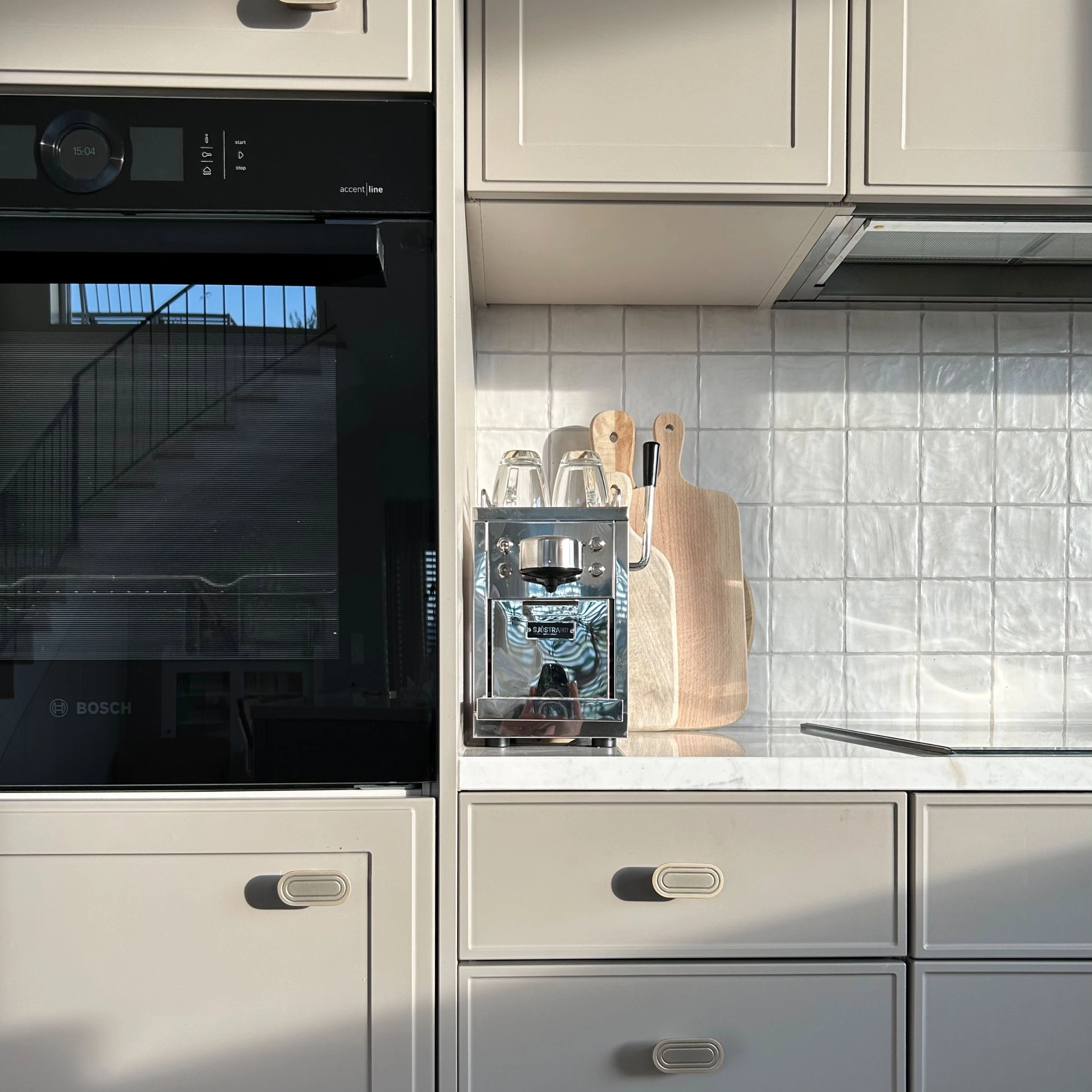 Cuisine moderne avec armoires blanches et détails en bois, parfaitement complétée par Nolte Kitchen.