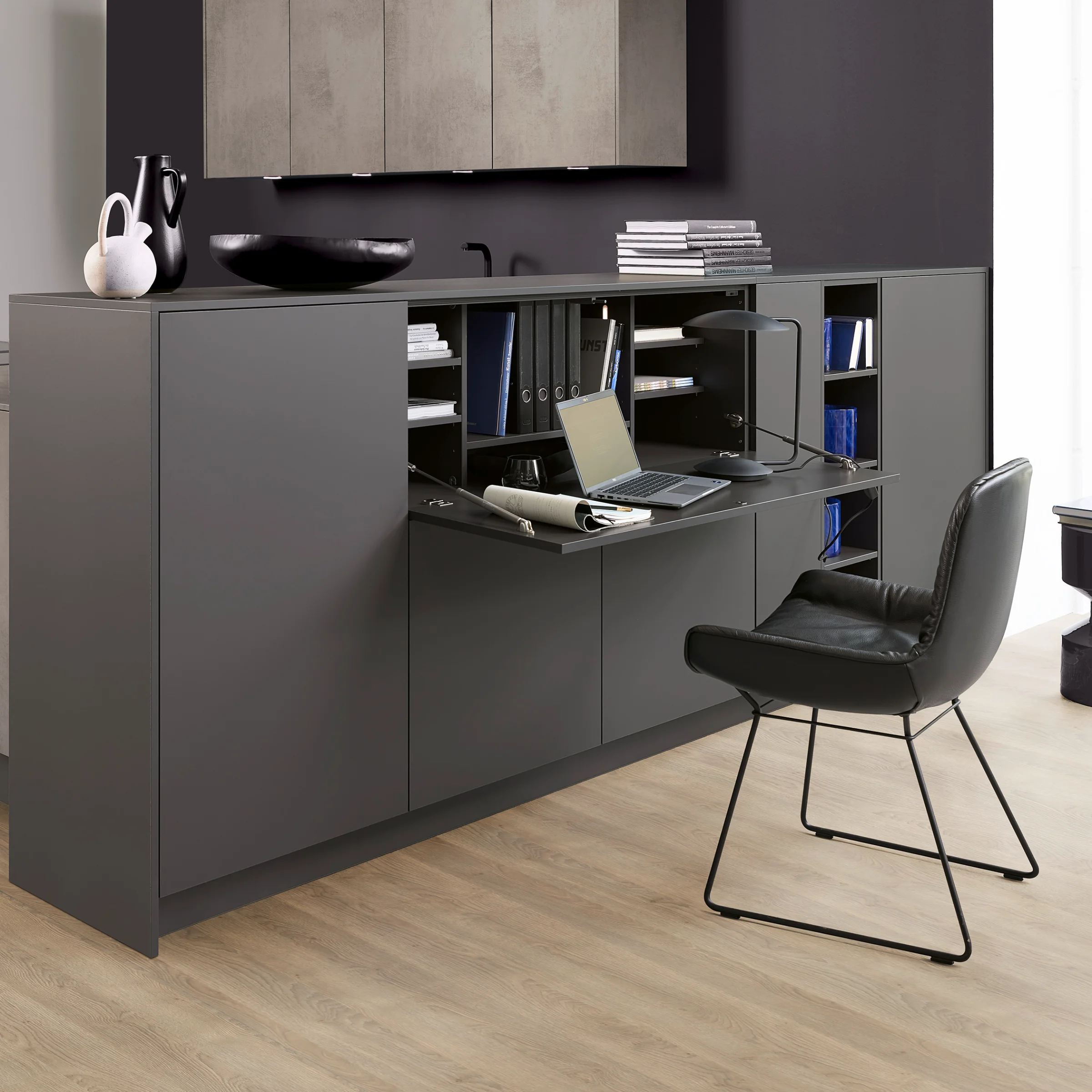 Un espace de vie moderne avec des armoires grises et une table pliante, Nolte Living.