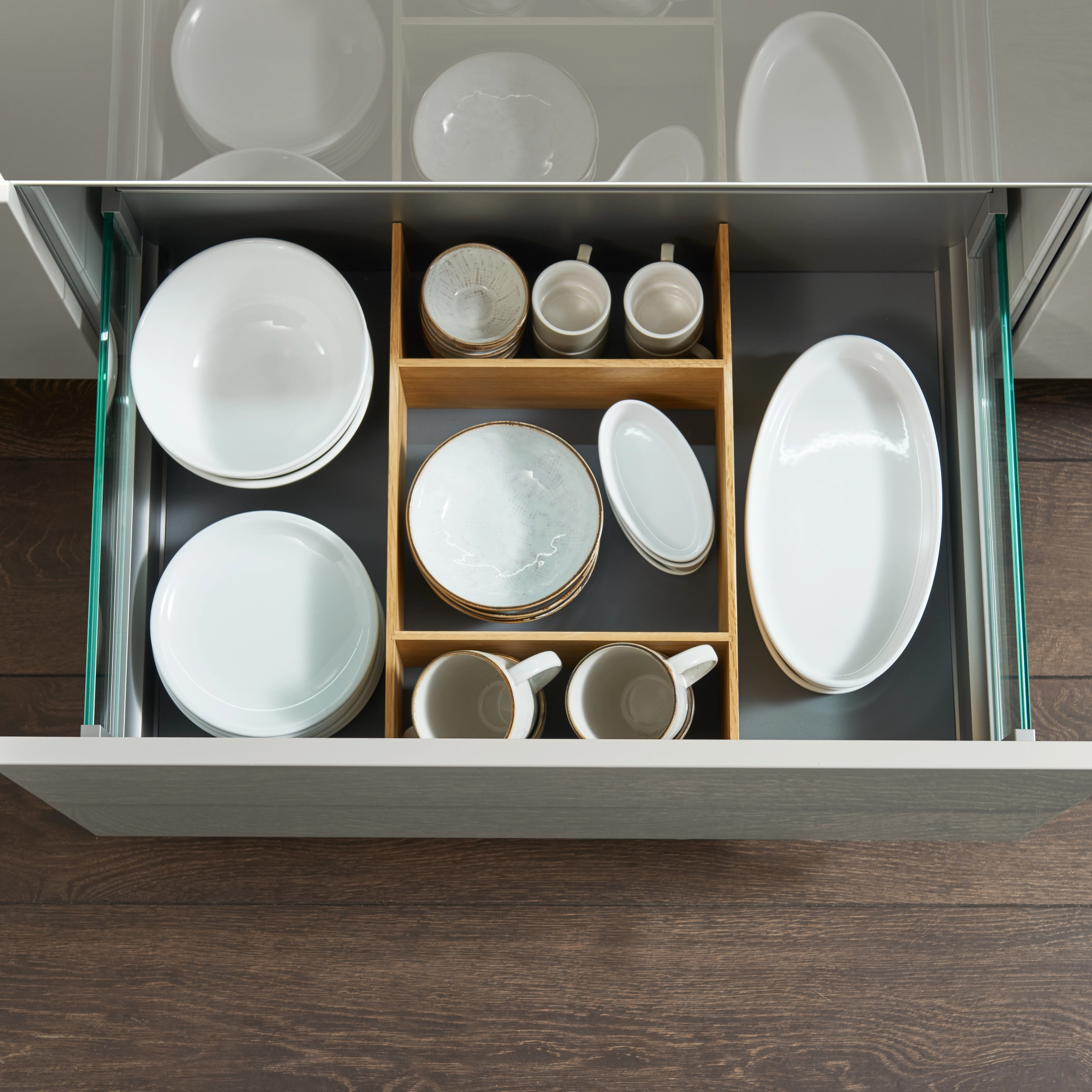 Un tiroir de cuisine ouvert avec vaisselle et compartiments en bois, Nolte Kitchen.
