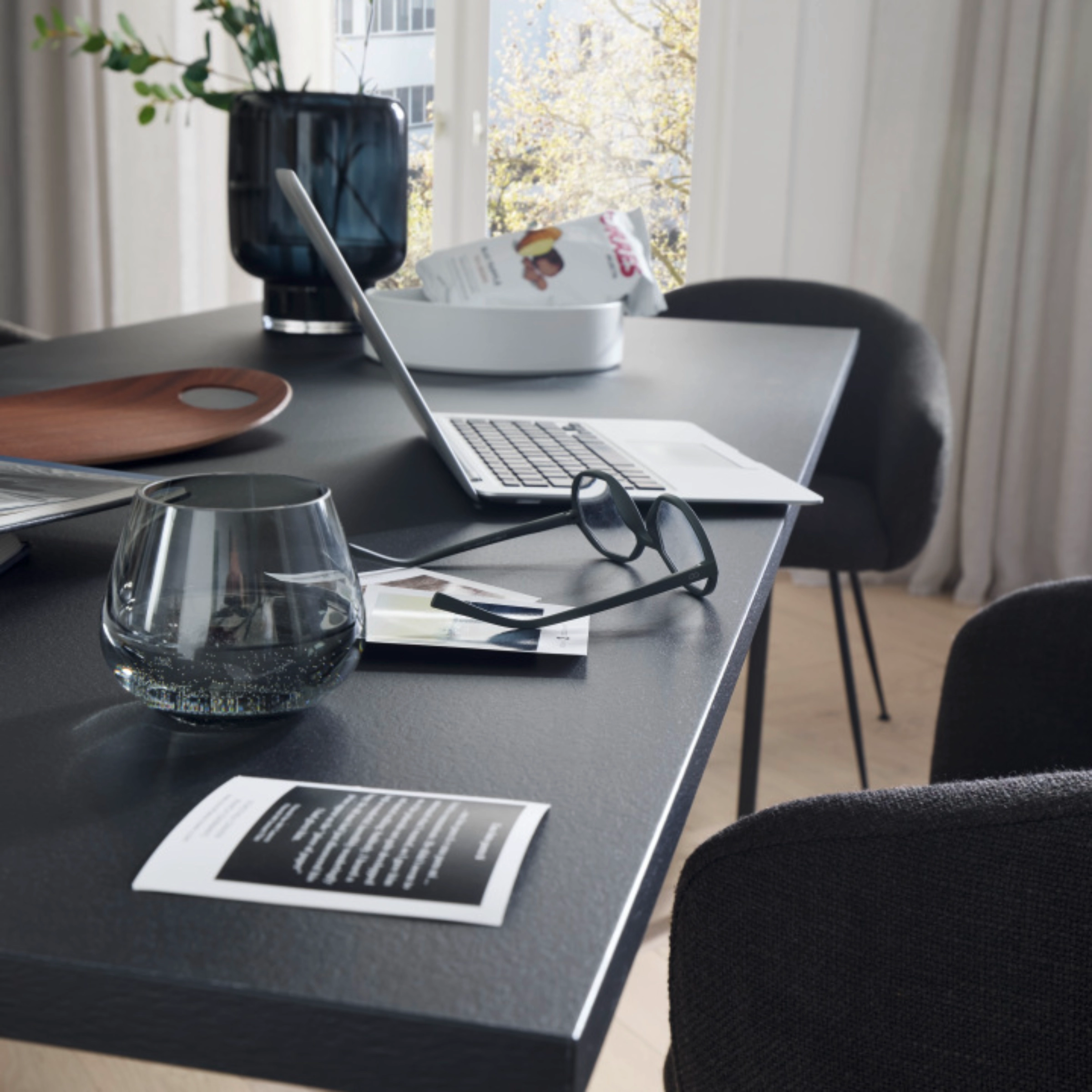 Un salon moderne avec table, ordinateur portable et éléments déco, assortis à Nolte Living.
