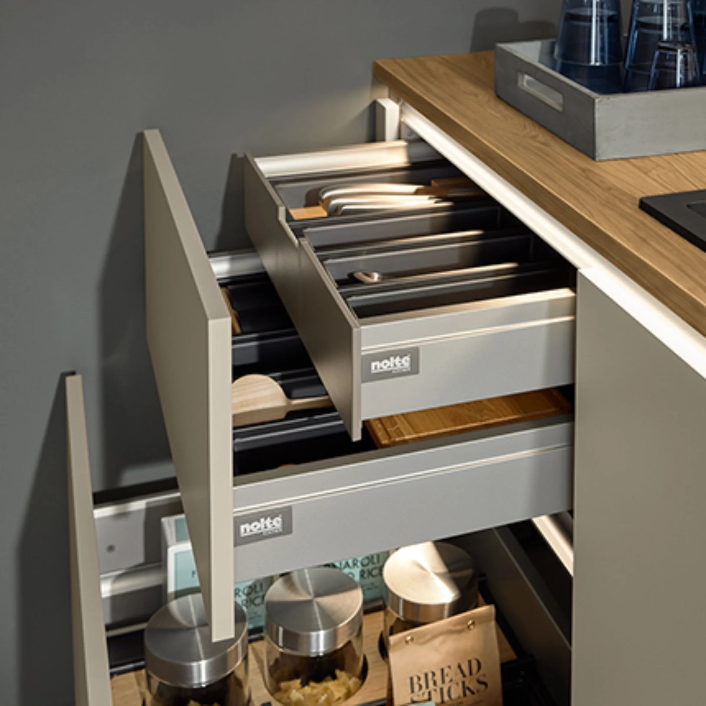 Moderne Küche mit offenen Schubladen und Holzarbeitsplatte. Nolte Küchen.