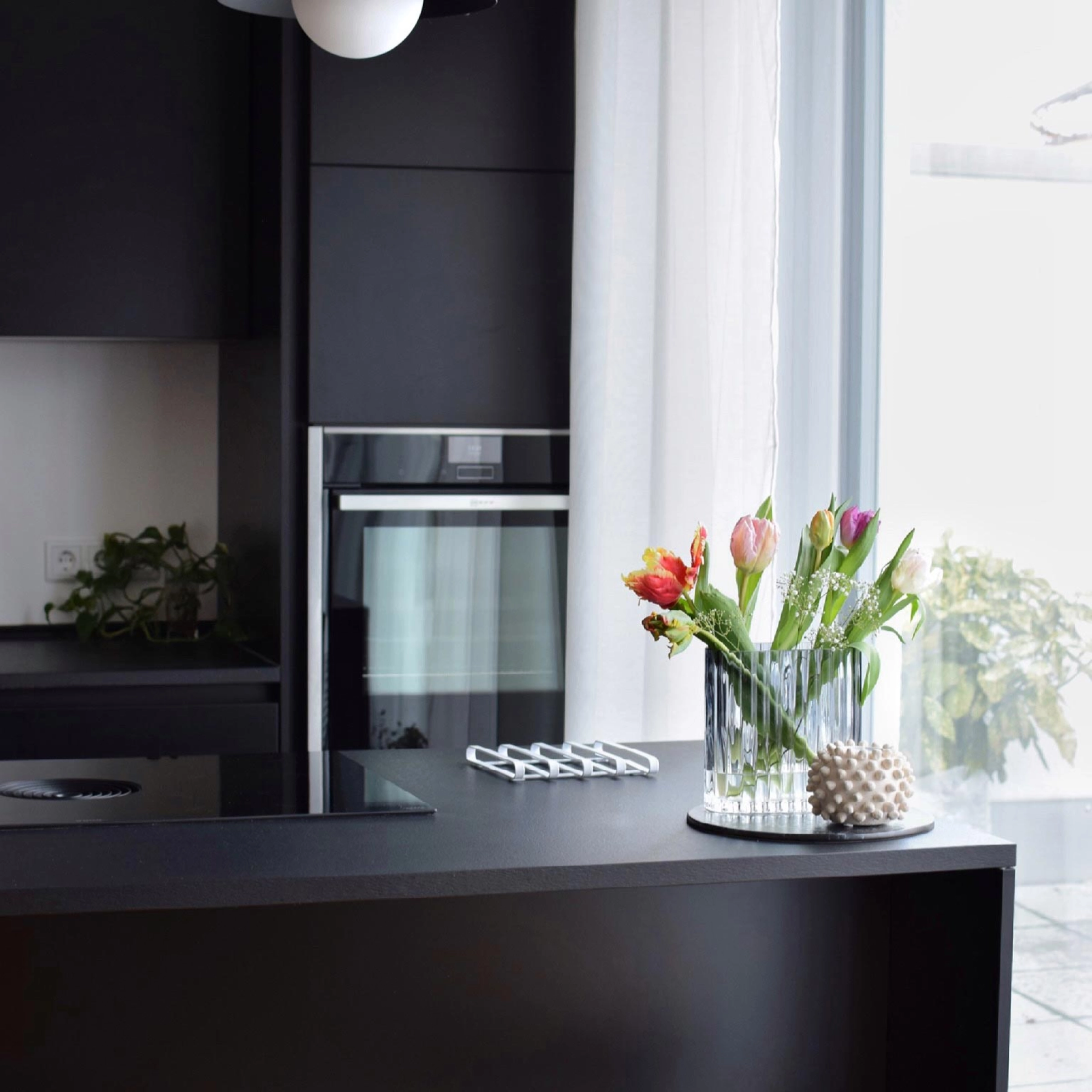 Cuisine moderne avec plan de travail noir et fleurs colorées, conçue par Nolte Kitchen.