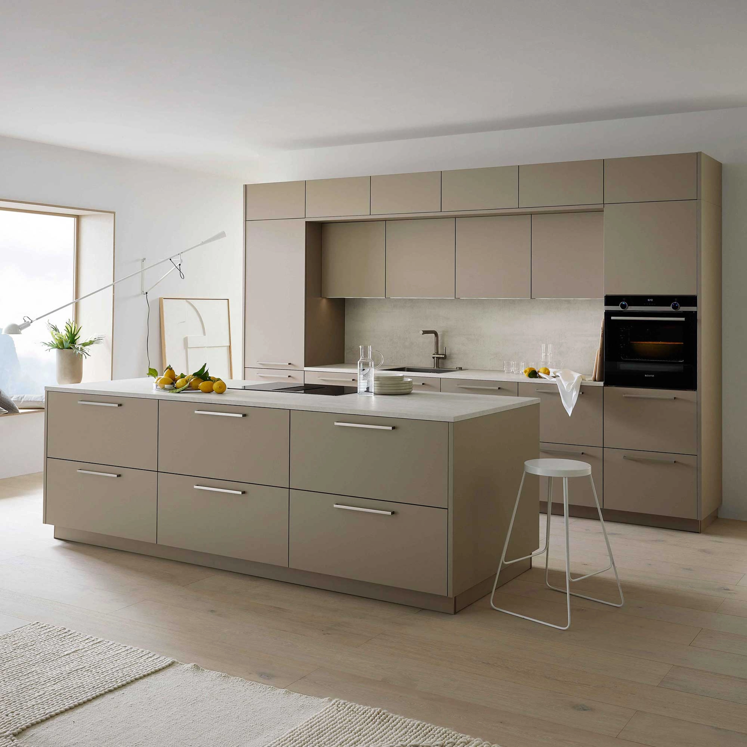 A modern kitchen with an island and appliances, designed by Nolte Kitchen.
