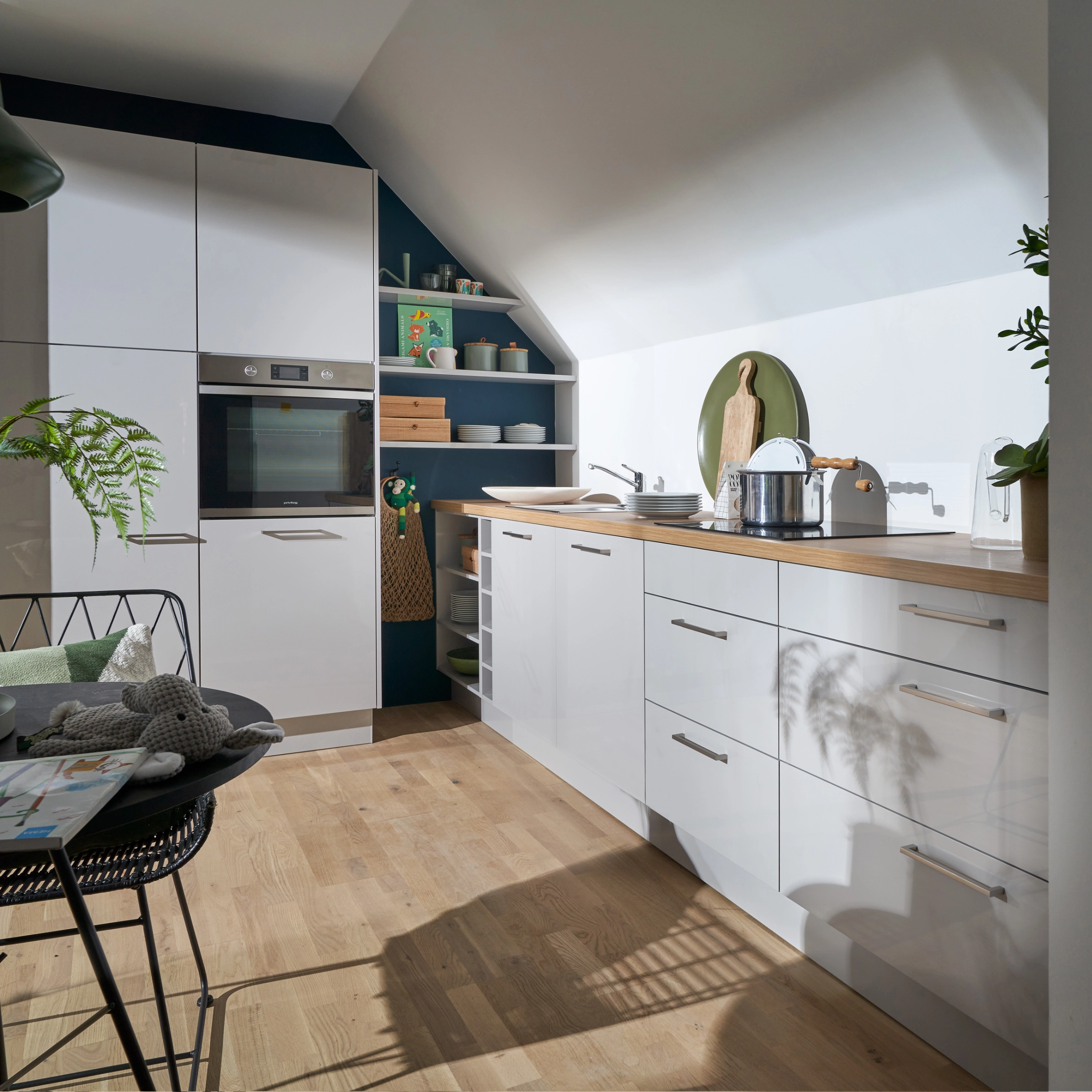 Moderne keuken met witte kasten en houten werkblad onder een schuin dak, Nolte Kitchen.