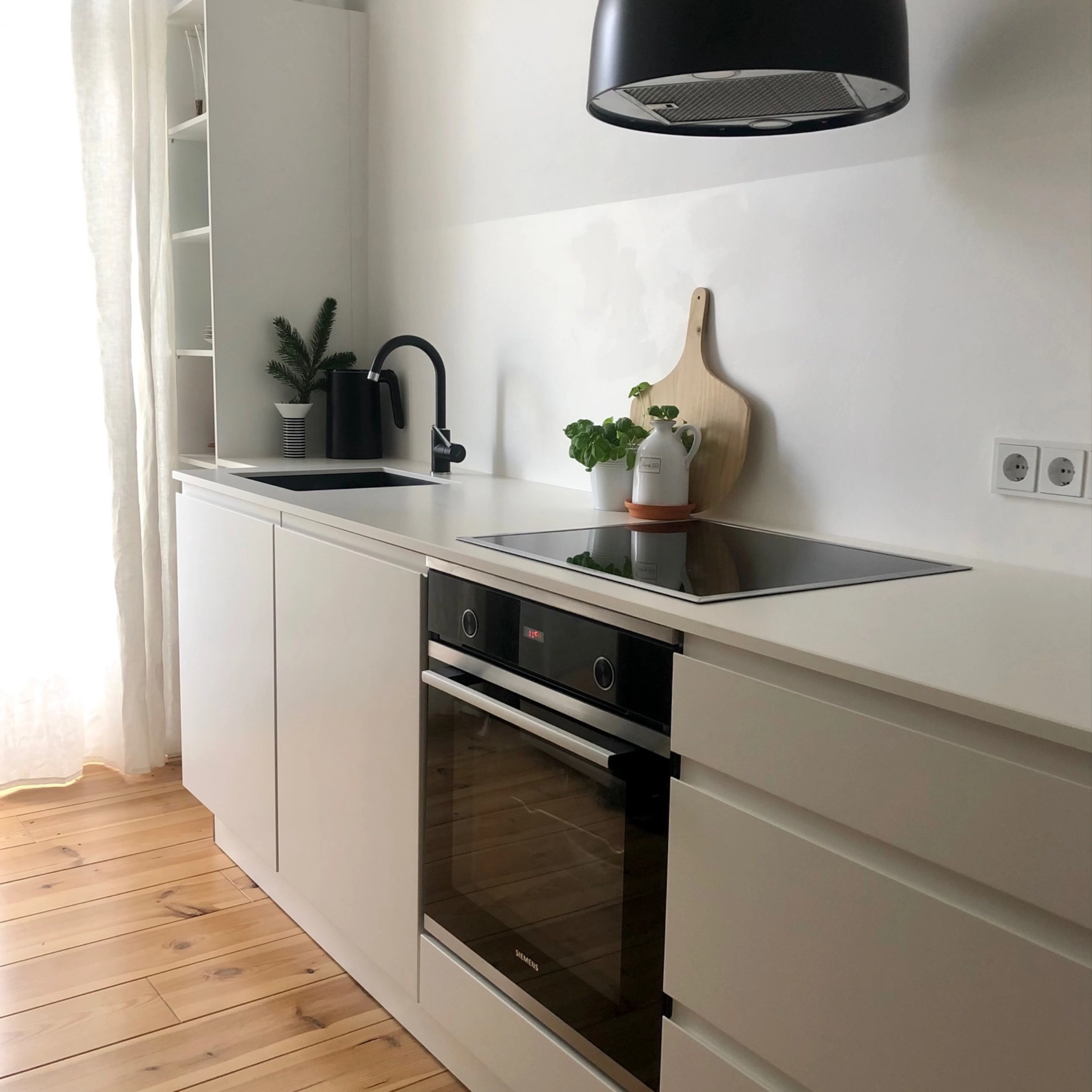 Cuisine moderne avec armoires blanches et sol en bois de Nolte Kitchen.