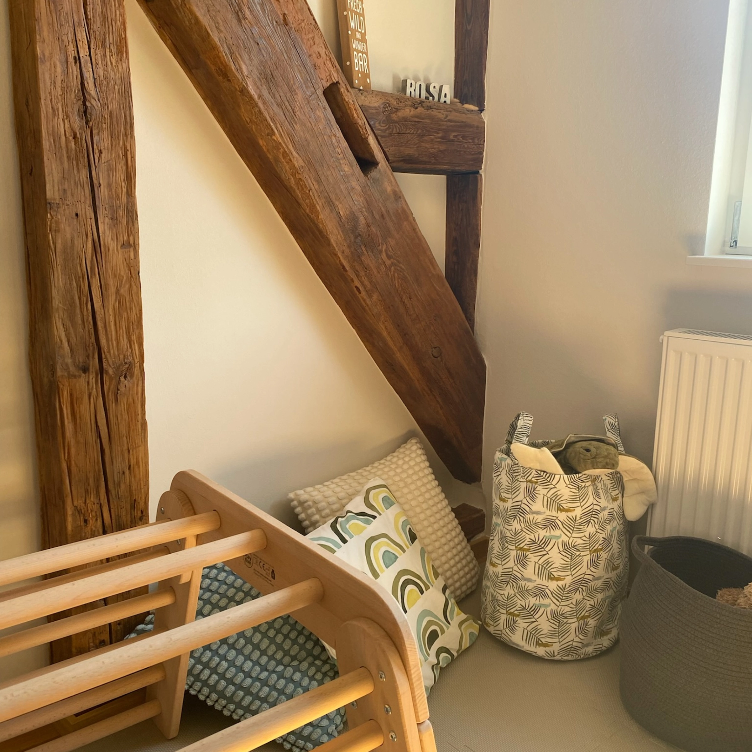 Une pièce chaleureuse avec poutres en bois, coussins et paniers présente Nolte Living.