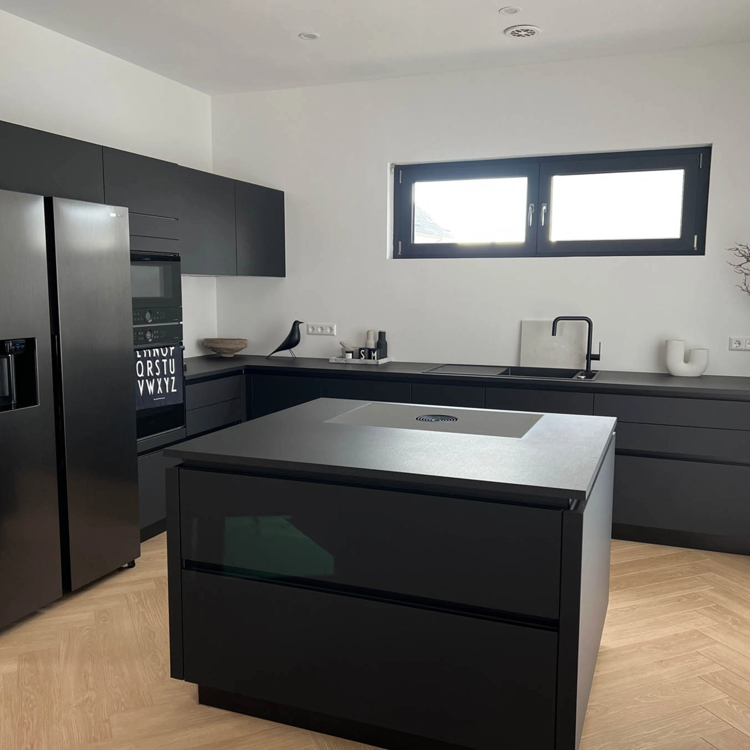 Cucina moderna con isola nera e elettrodomestici, progettata da Nolte Kitchen.