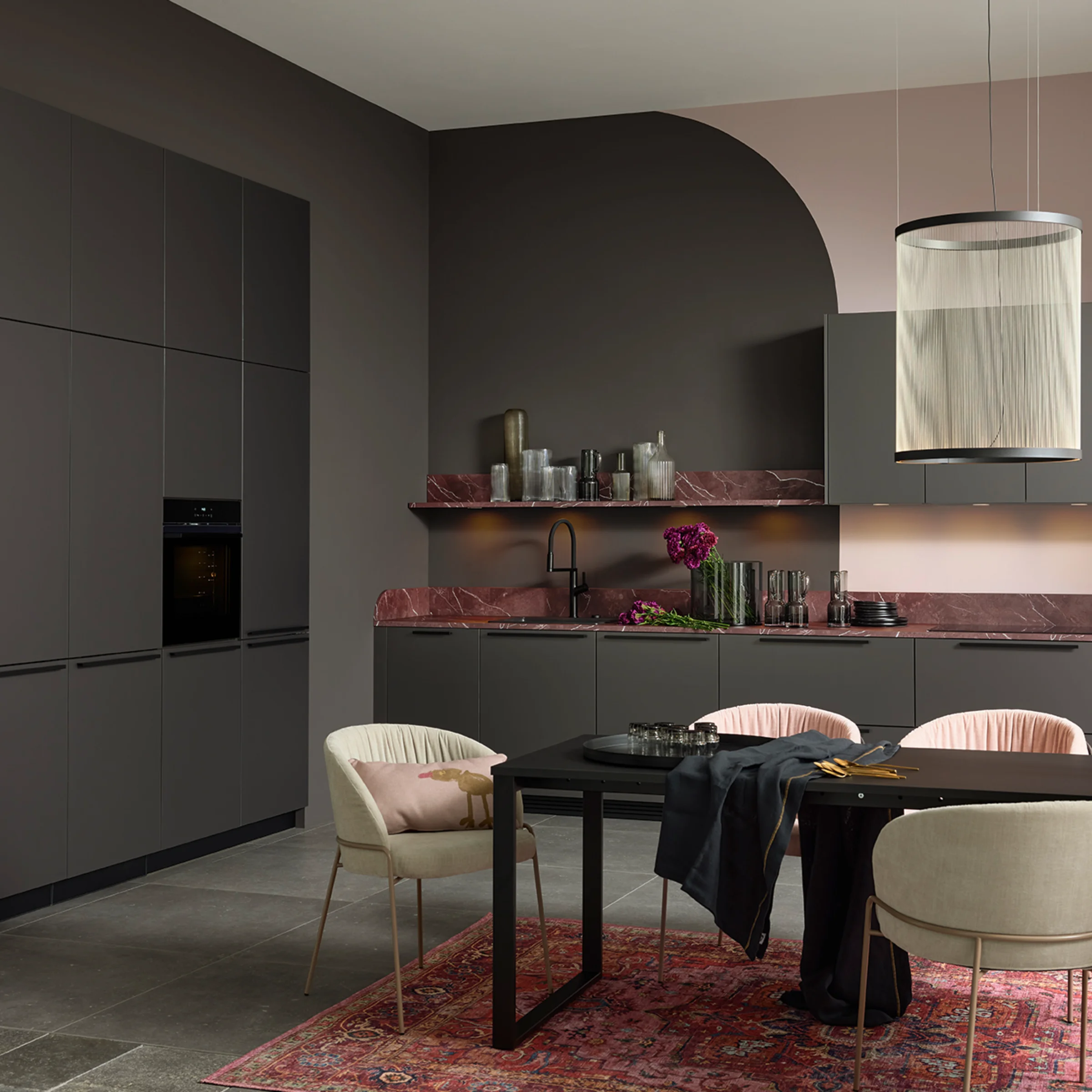 A modern kitchen with dark cabinets and a sleek dining table. Nolte Küchen.