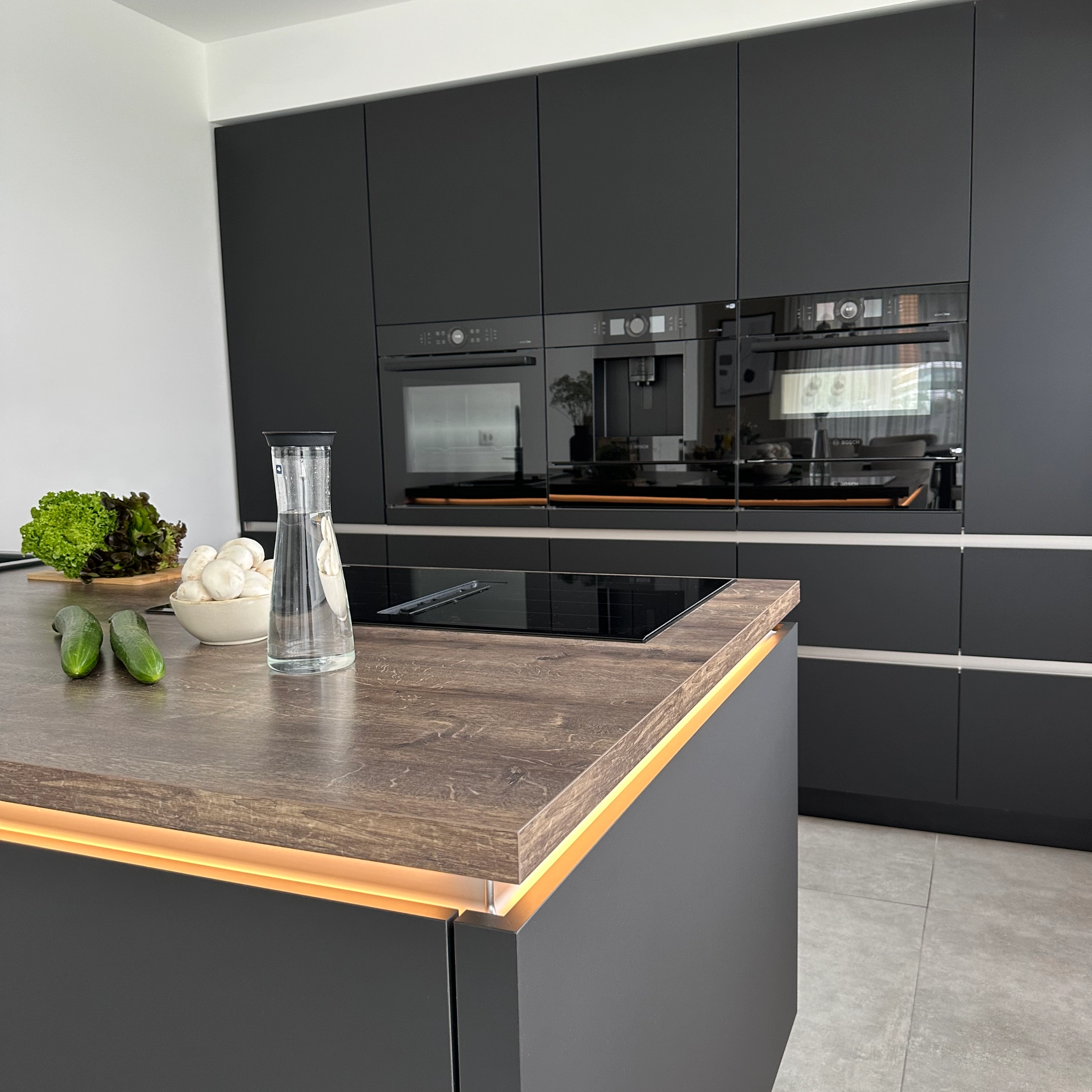A modern kitchen with dark cabinets and an island, stylishly designed by Nolte Kitchen.