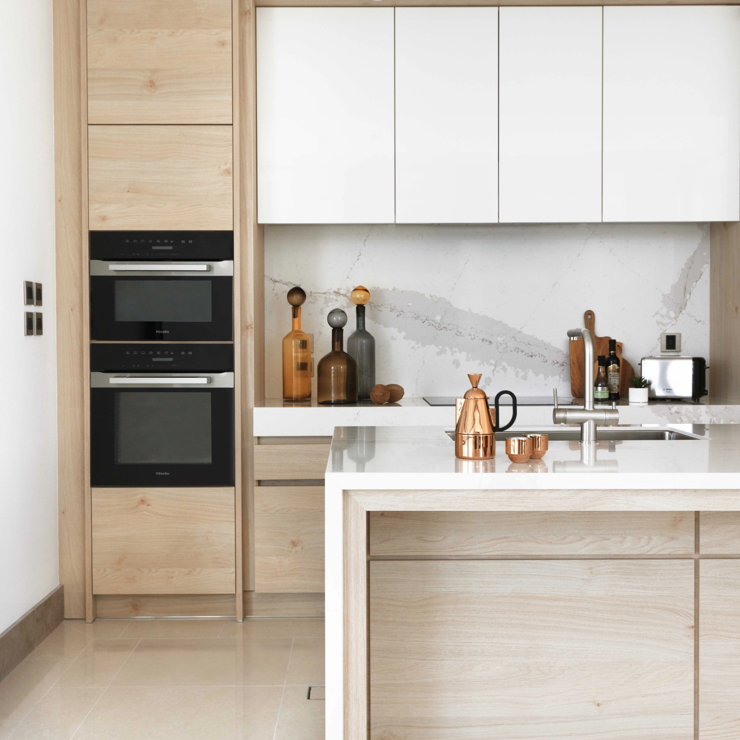 Eine moderne Küche mit Holz- und Weißtönen, ausgestattet mit Geräten und Accessoires. Nolte Küchen.