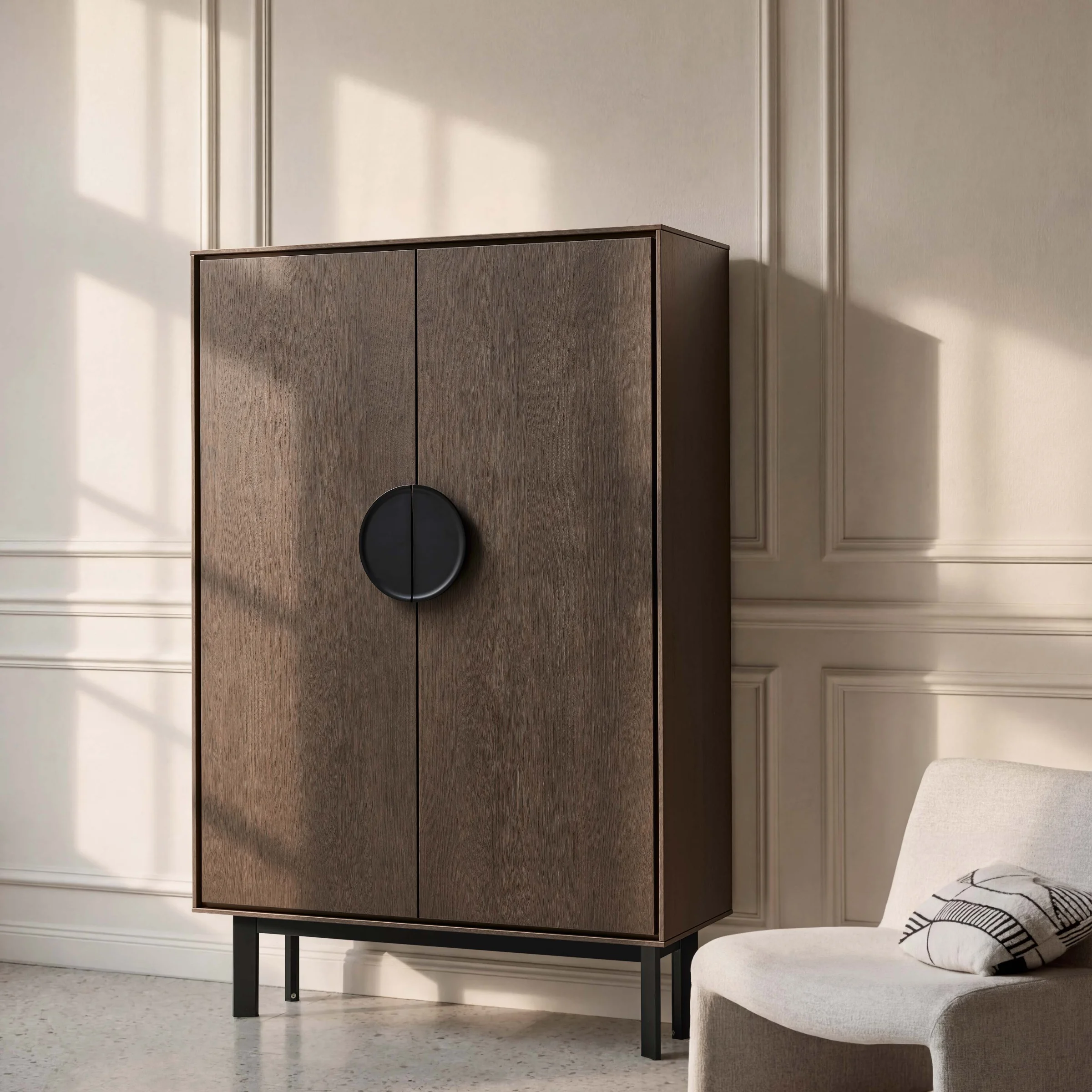 An elegant cabinet stands next to a beige armchair, Nolte Living.