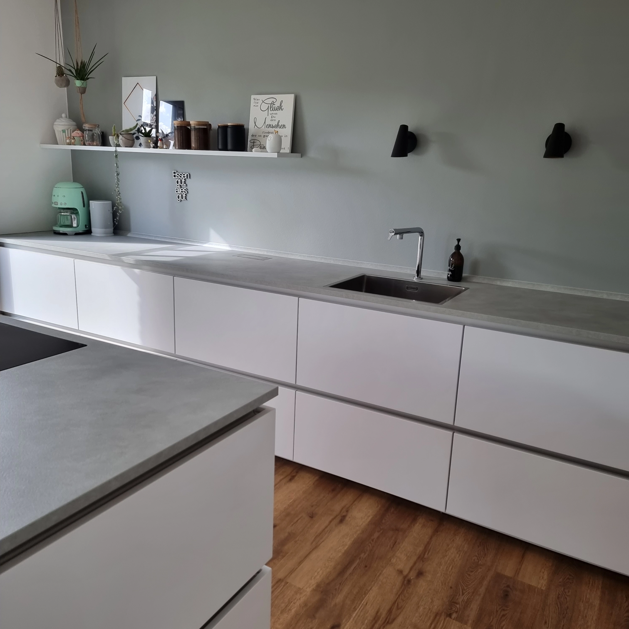 Een moderne keuken met witte kasten en houten vloer, gepresenteerd door Nolte Kitchen.
