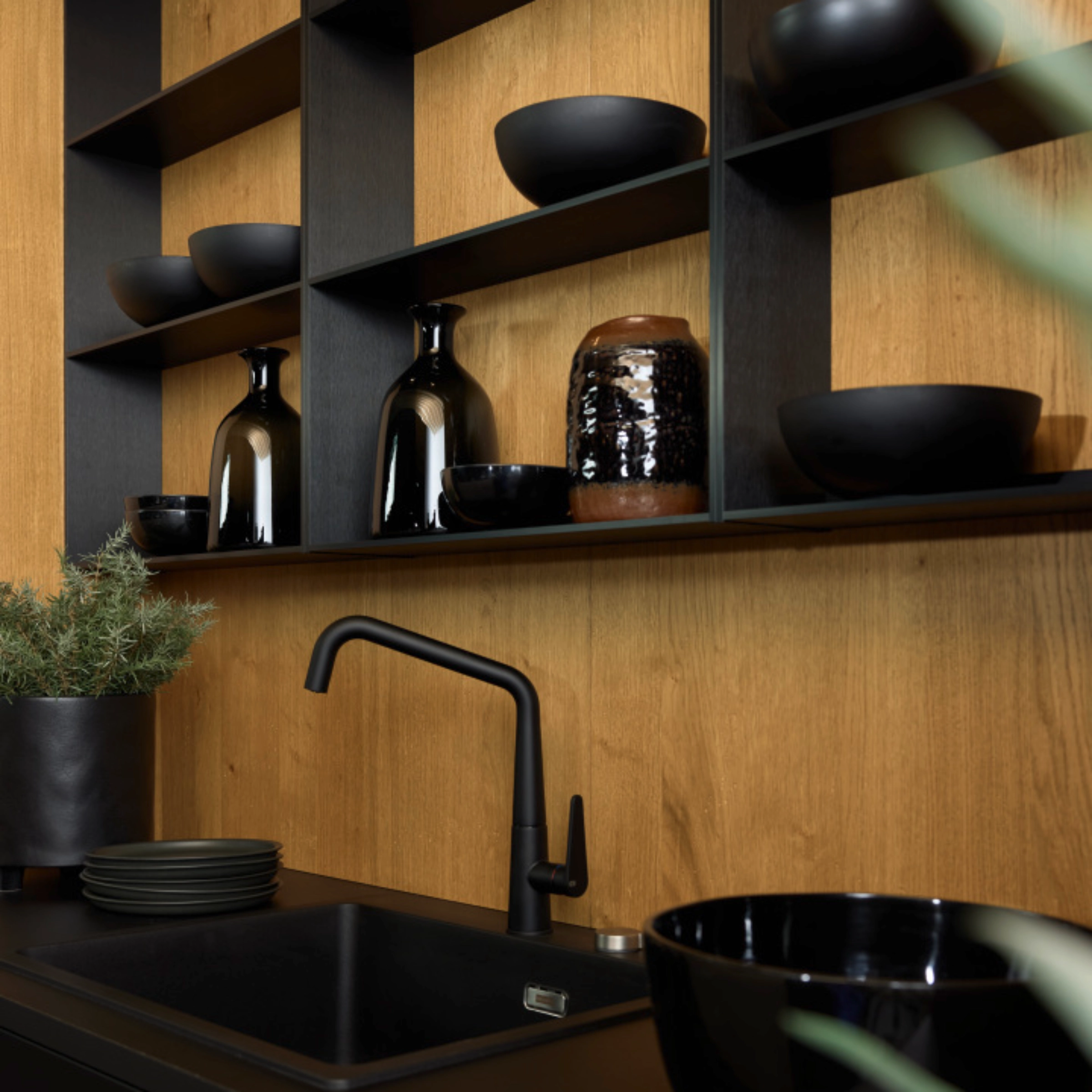 Cuisine moderne avec plan de travail noir et étagères en bois, conçue par Nolte Kitchen.