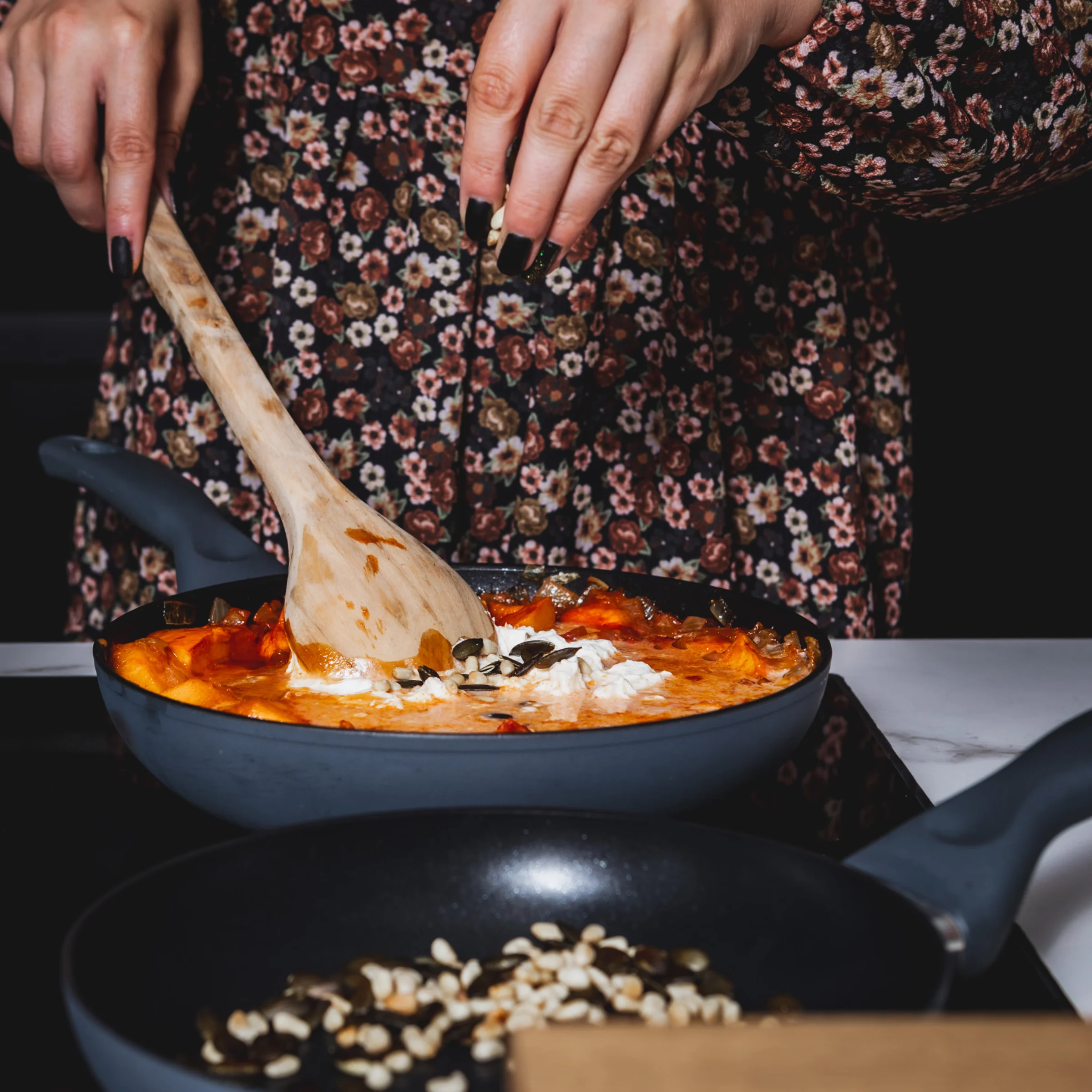 Person kocht in einer modernen Küche mit zwei Pfannen. Nolte Küchen Rezept.