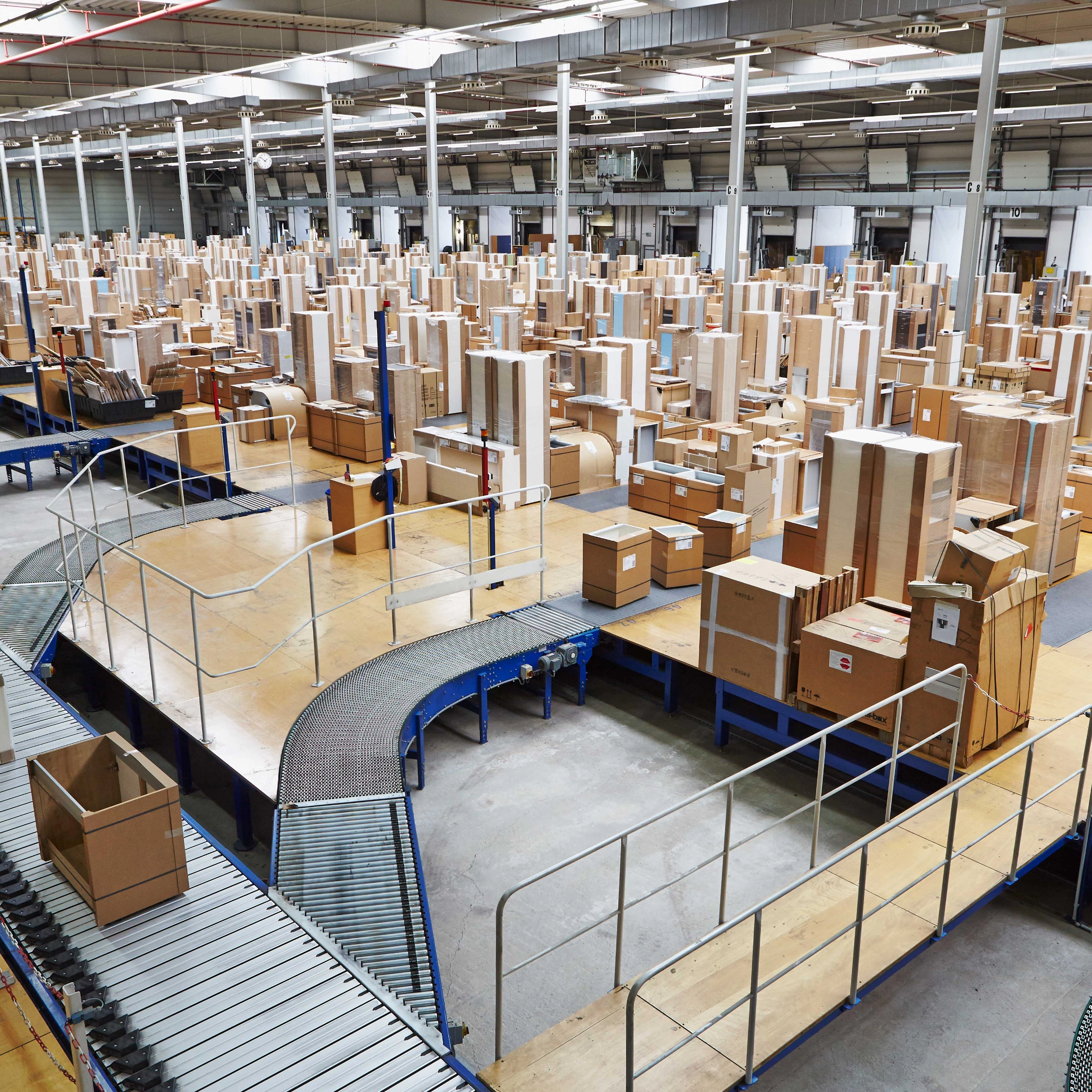 Un grand entrepôt rempli de cartons et de tapis roulants, lié à Nolte Kitchen.