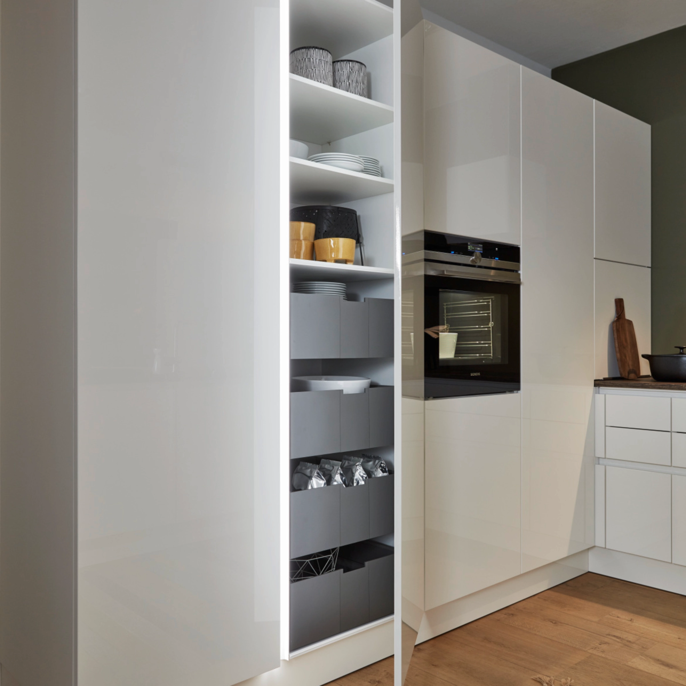 A modern kitchen with white cabinets and a built-in oven from Nolte Kitchen.