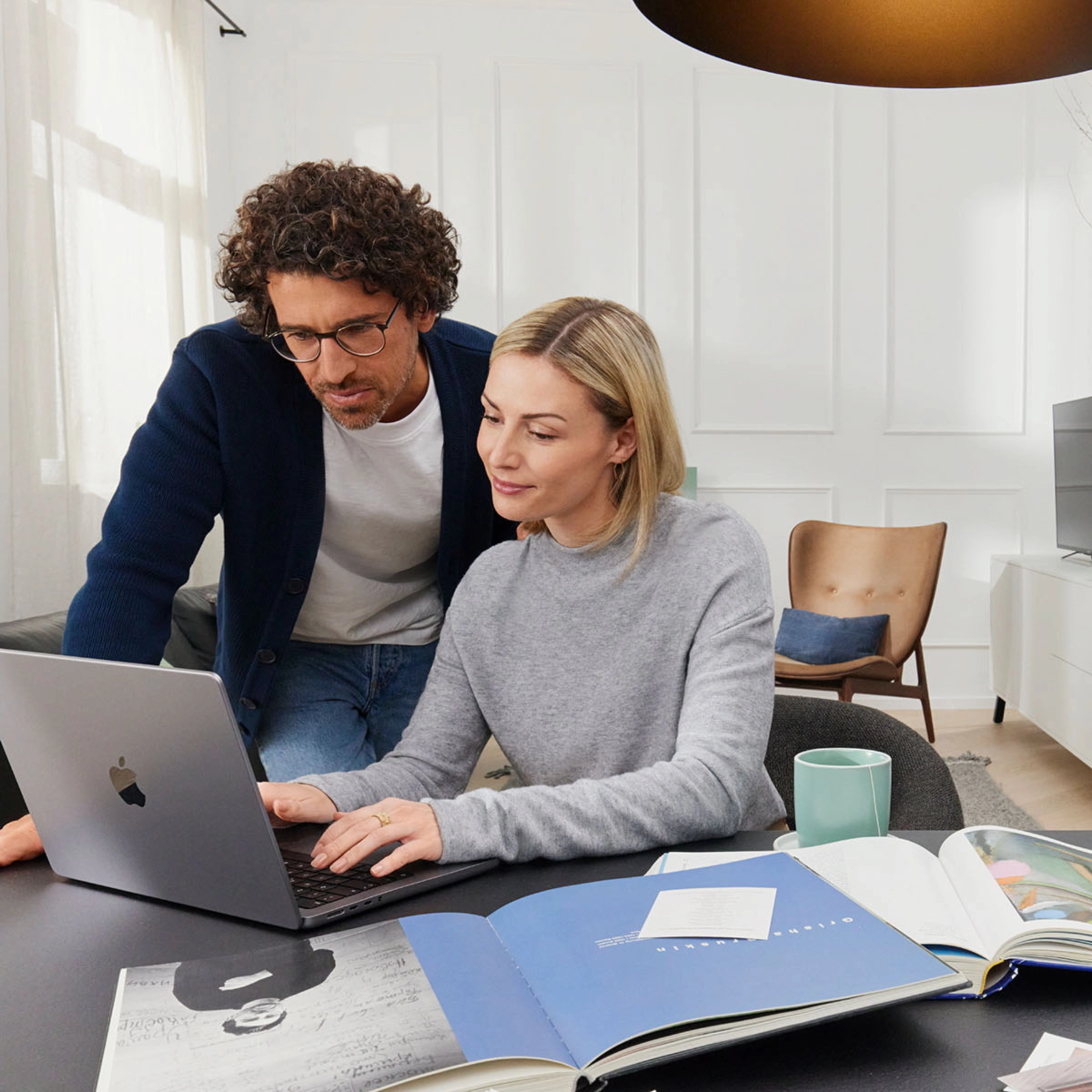 Un couple travaille ensemble sur un ordinateur portable dans un salon moderne avec Nolte Living.