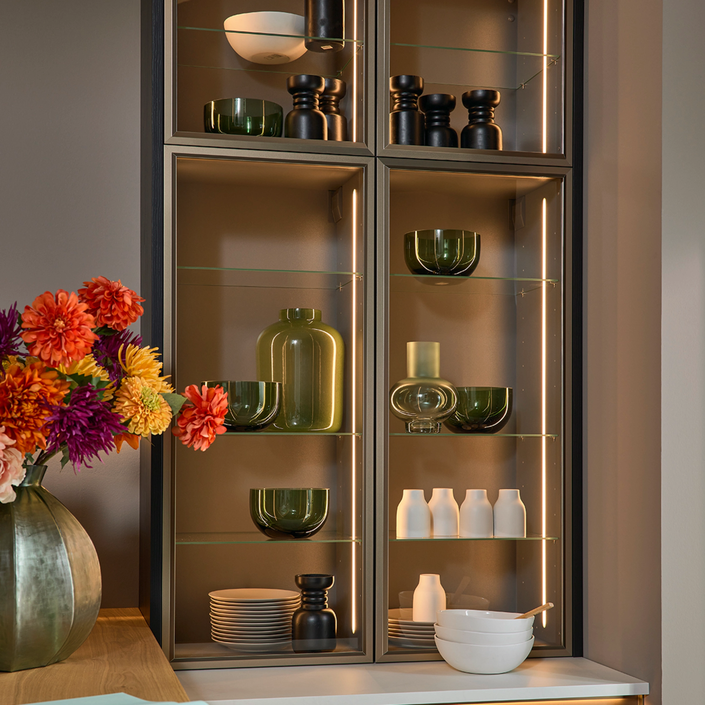 Une étagère de salon élégante avec vases en verre et vaisselle, assortie à Nolte Living.