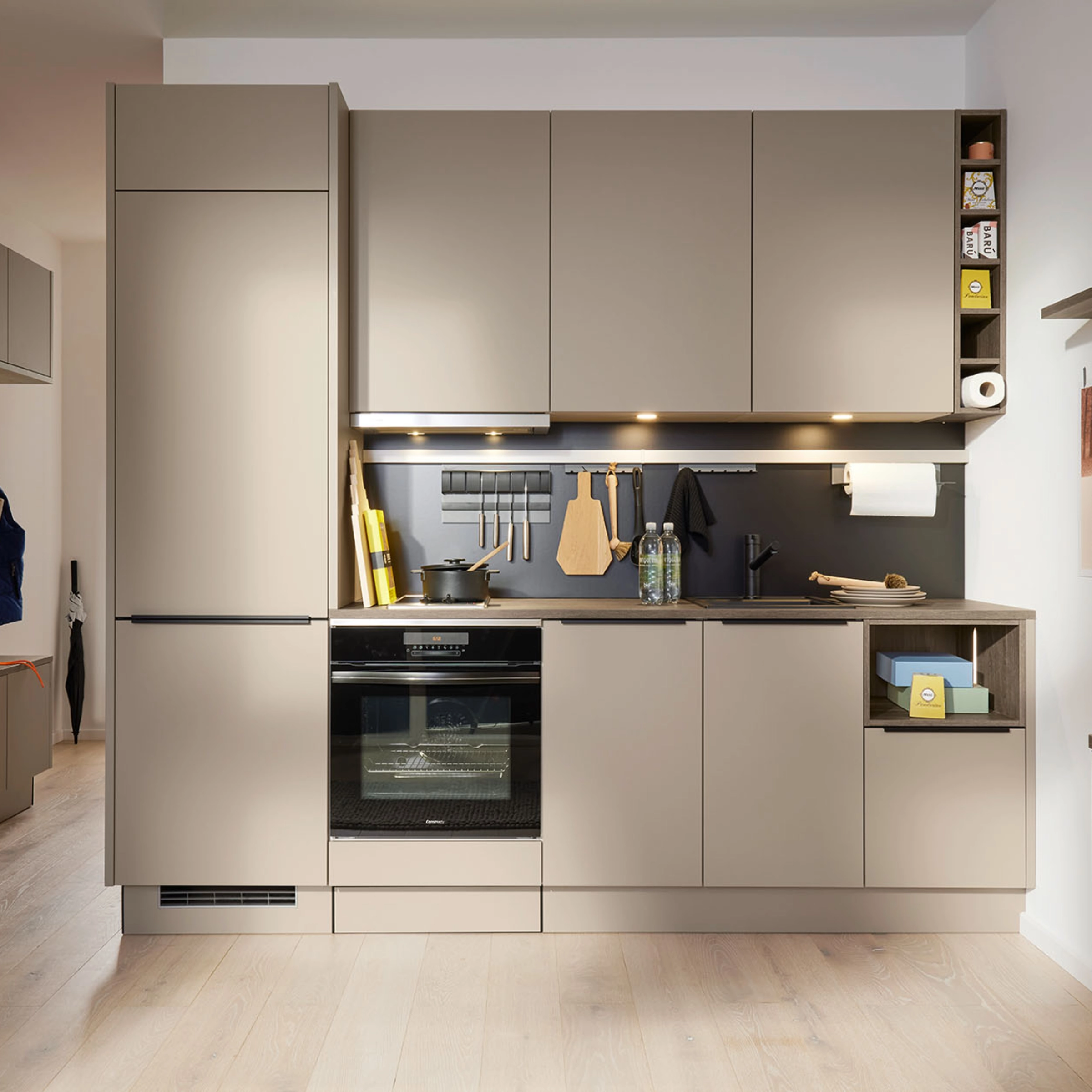 A modern kitchen with beige cabinets and integrated appliances; Nolte Kitchens.