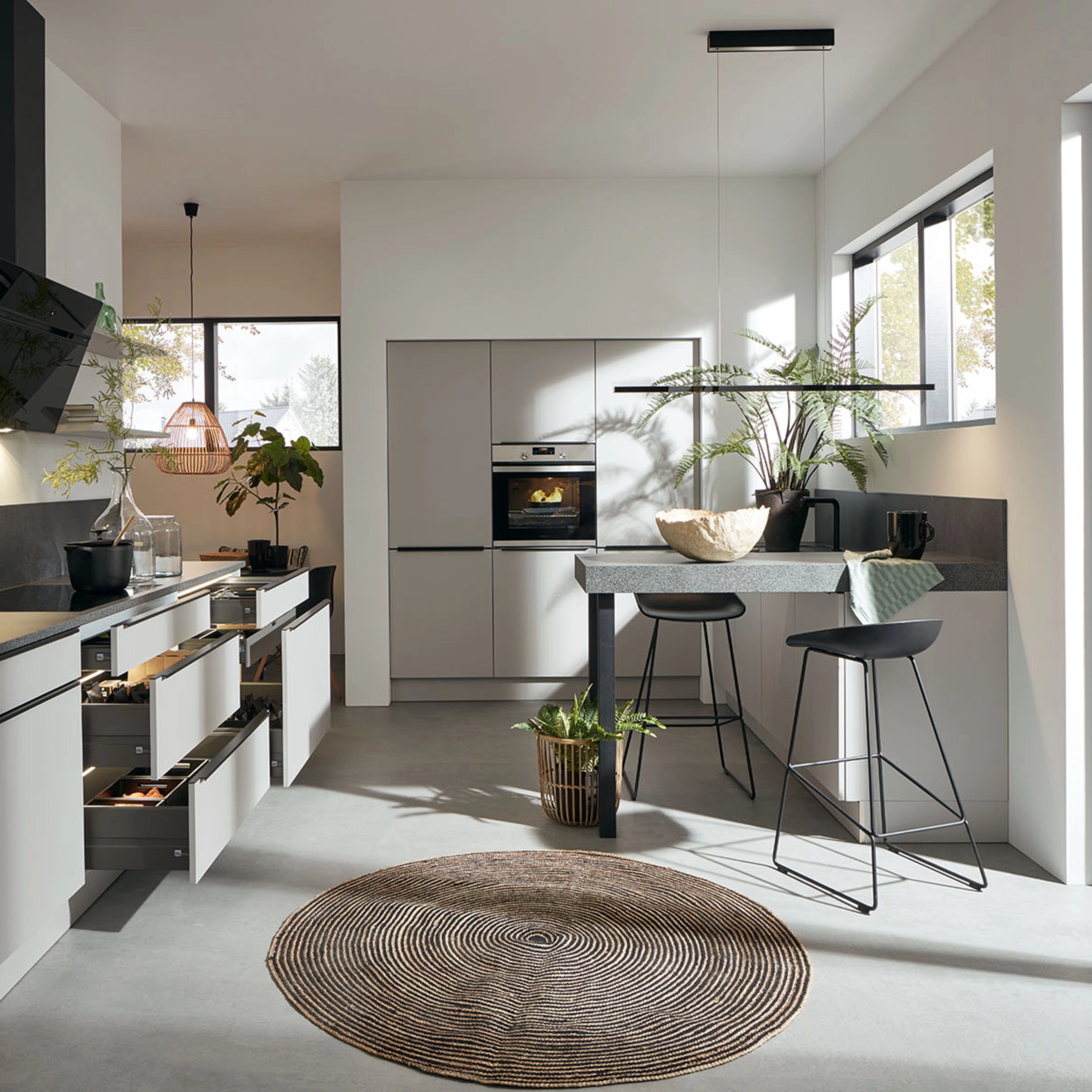 Nolte Cuisine: Cuisine moderne avec îlot, plan de travail en pierre et grandes fenêtres.