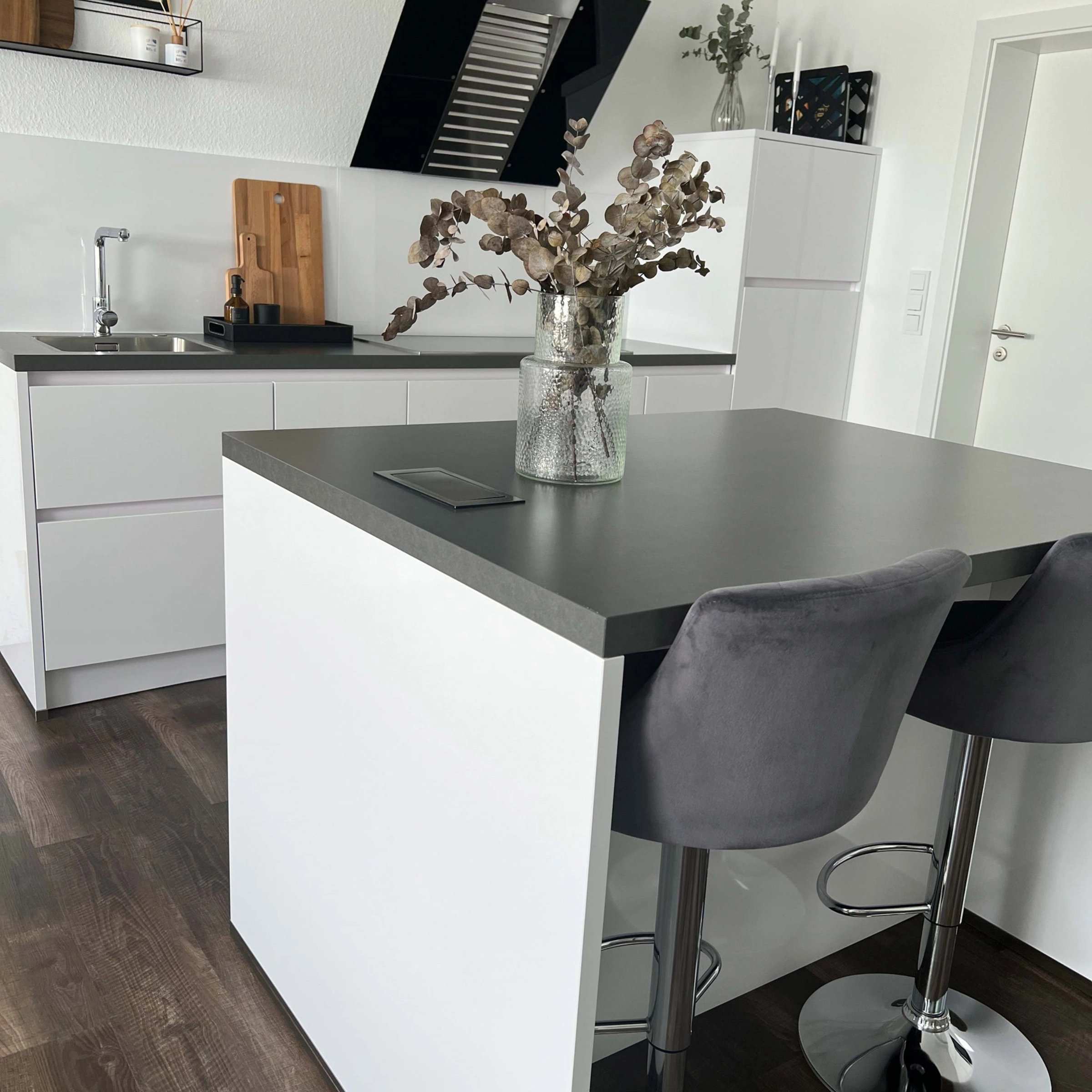 Cuisine moderne avec îlot et tabourets noirs, conçue par Nolte Kitchen.