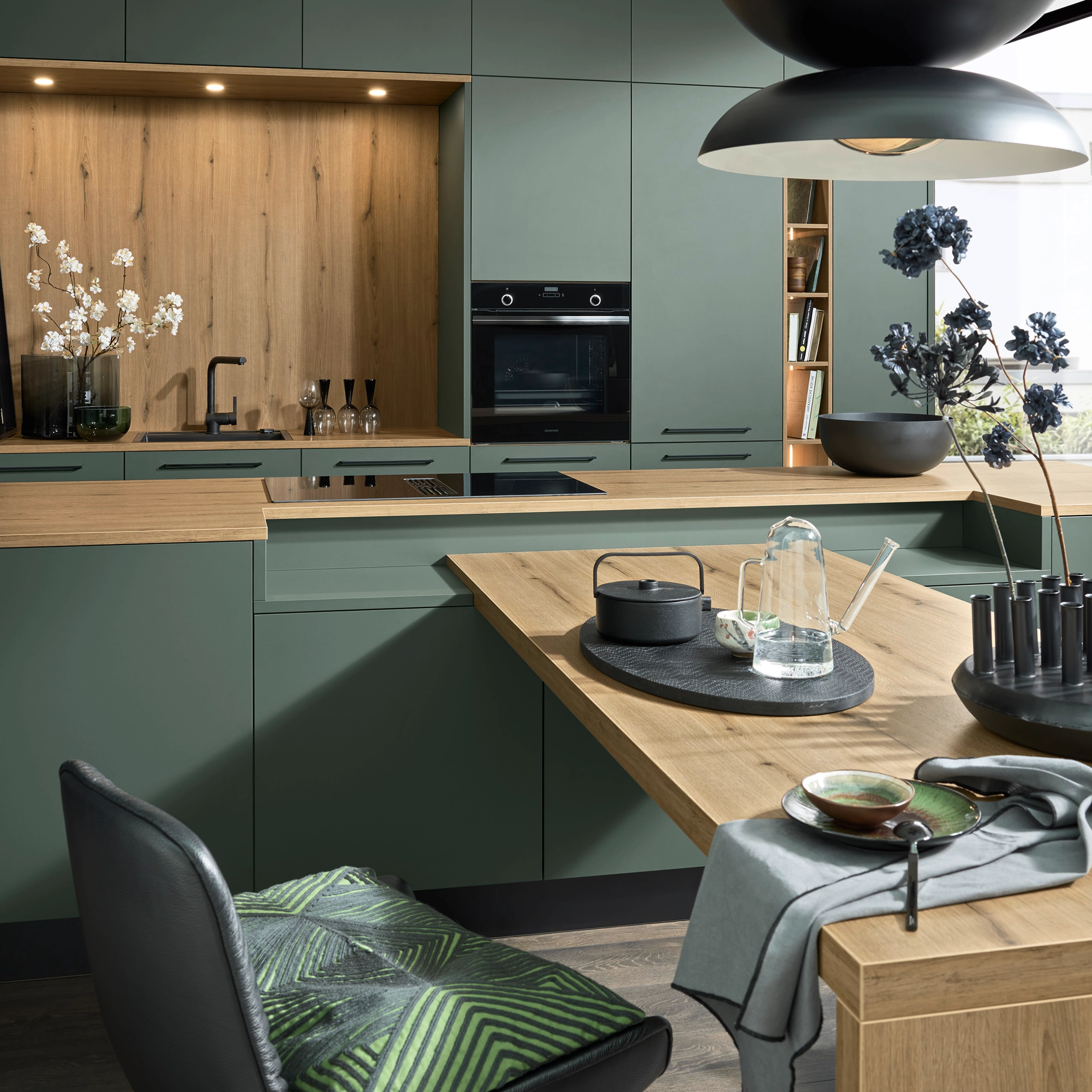 Une cuisine moderne en tons verts avec accents bois et décorations élégantes de Nolte Kitchen.