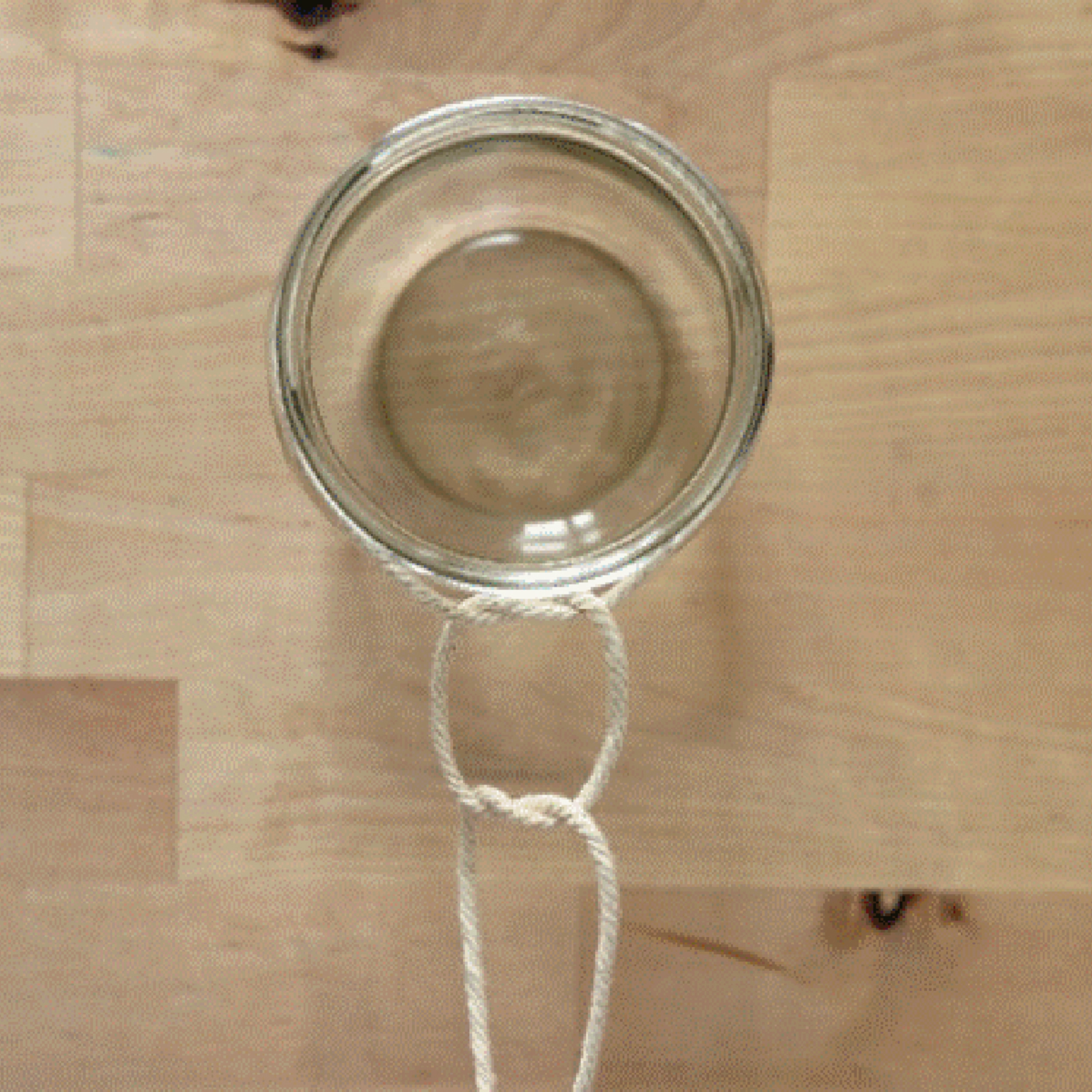 Un verre est attaché avec une corde à un récipient suspendu.