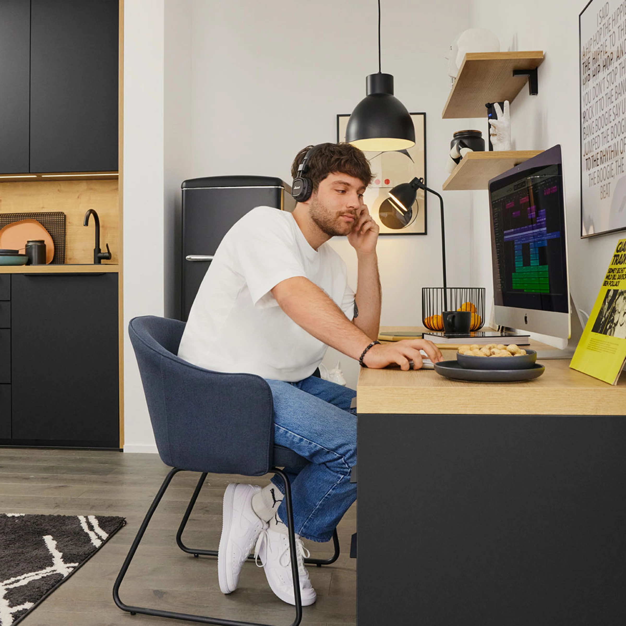 Un homme travaille dans une cuisine moderne de Nolte Kitchen, assis à un bureau avec un ordinateur.