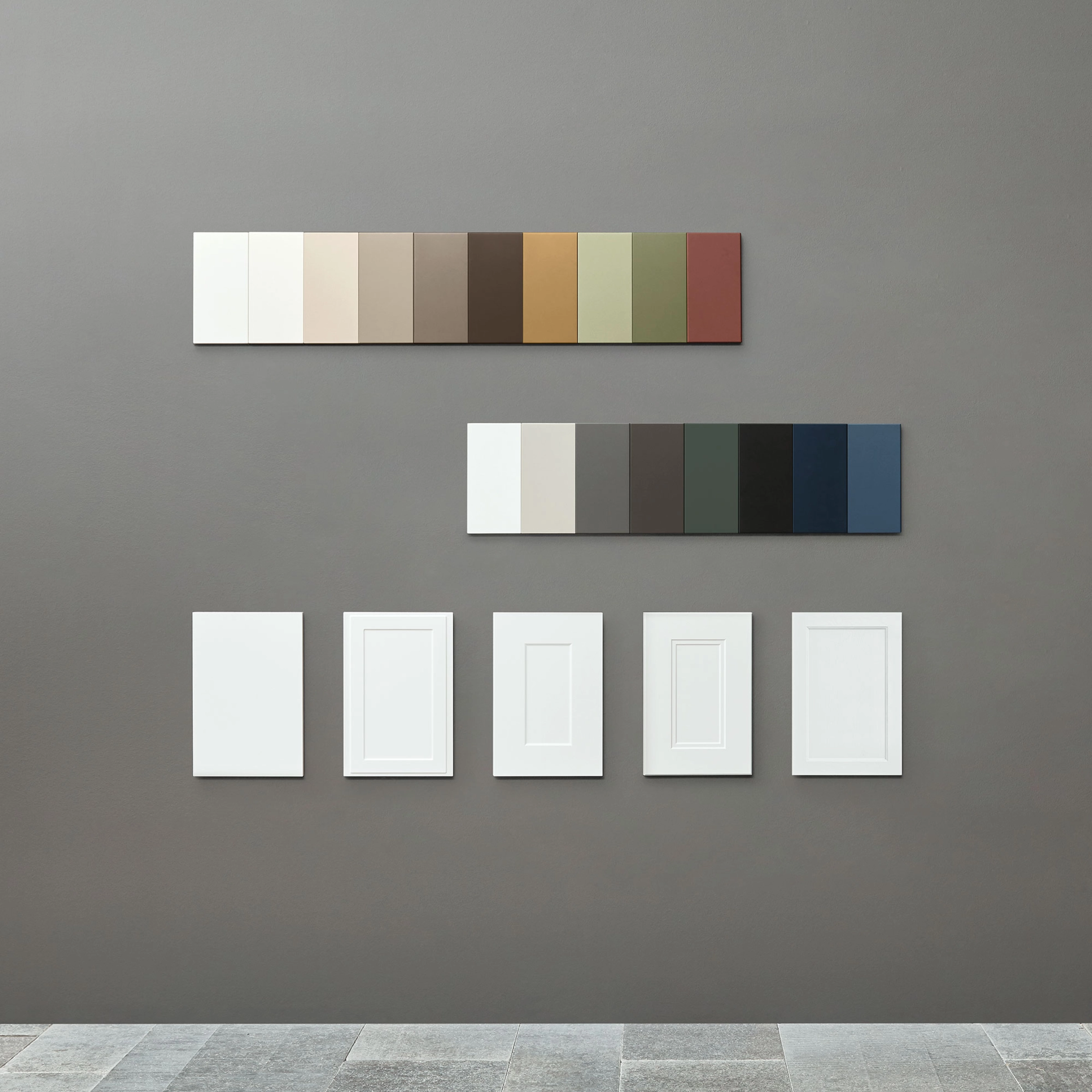 Farbmuster und Rahmen sind an einer grauen Wand ausgestellt, passend zu Nolte Living.
