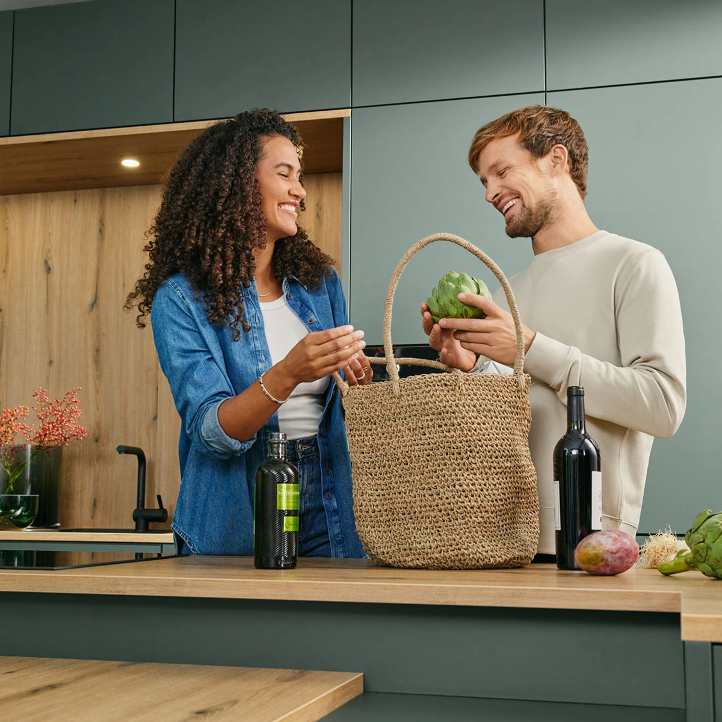 Un couple déballe des légumes dans une cuisine moderne Nolte.