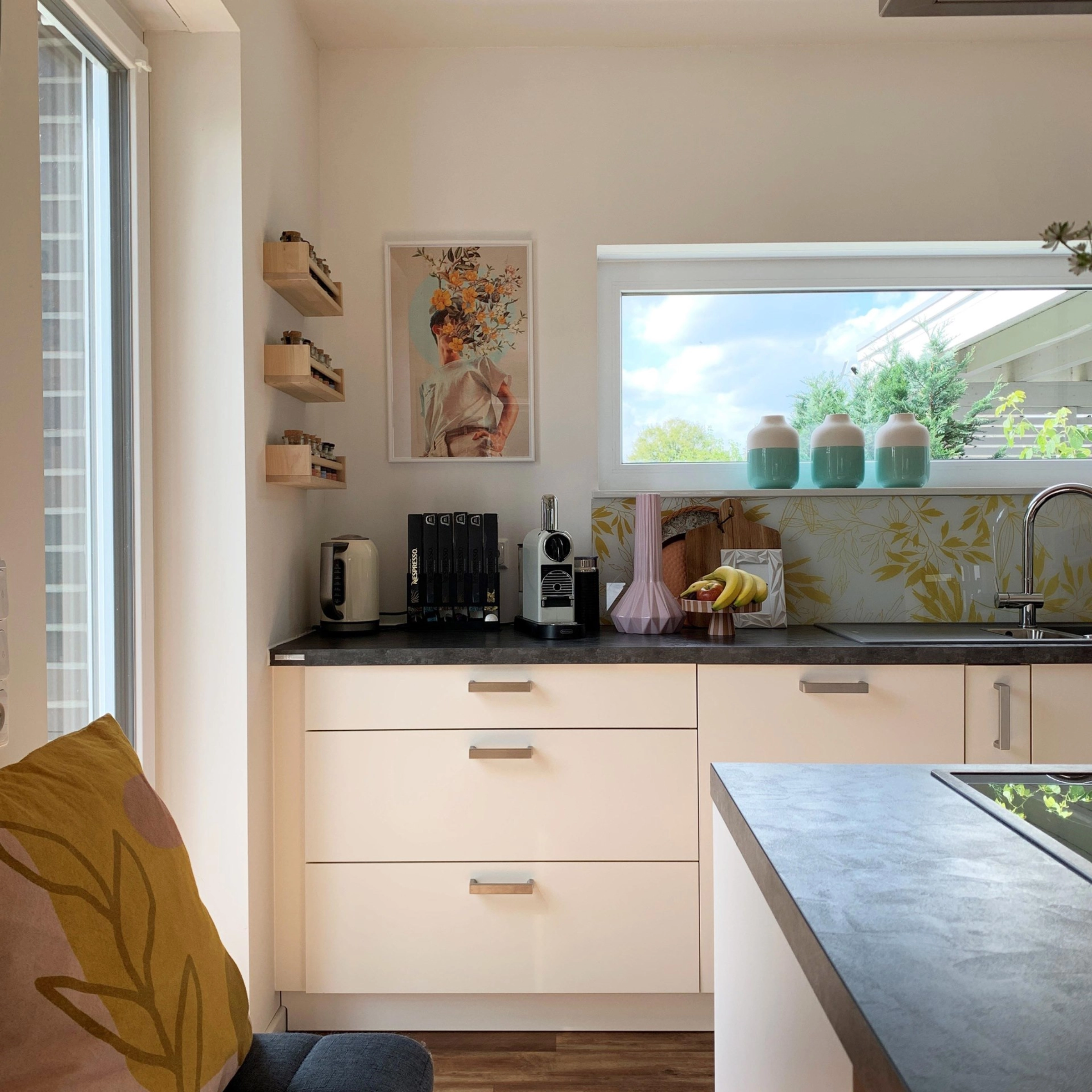 Bright kitchen with modern appliances and decor, including a painting on the wall. Nolte Kitchens.