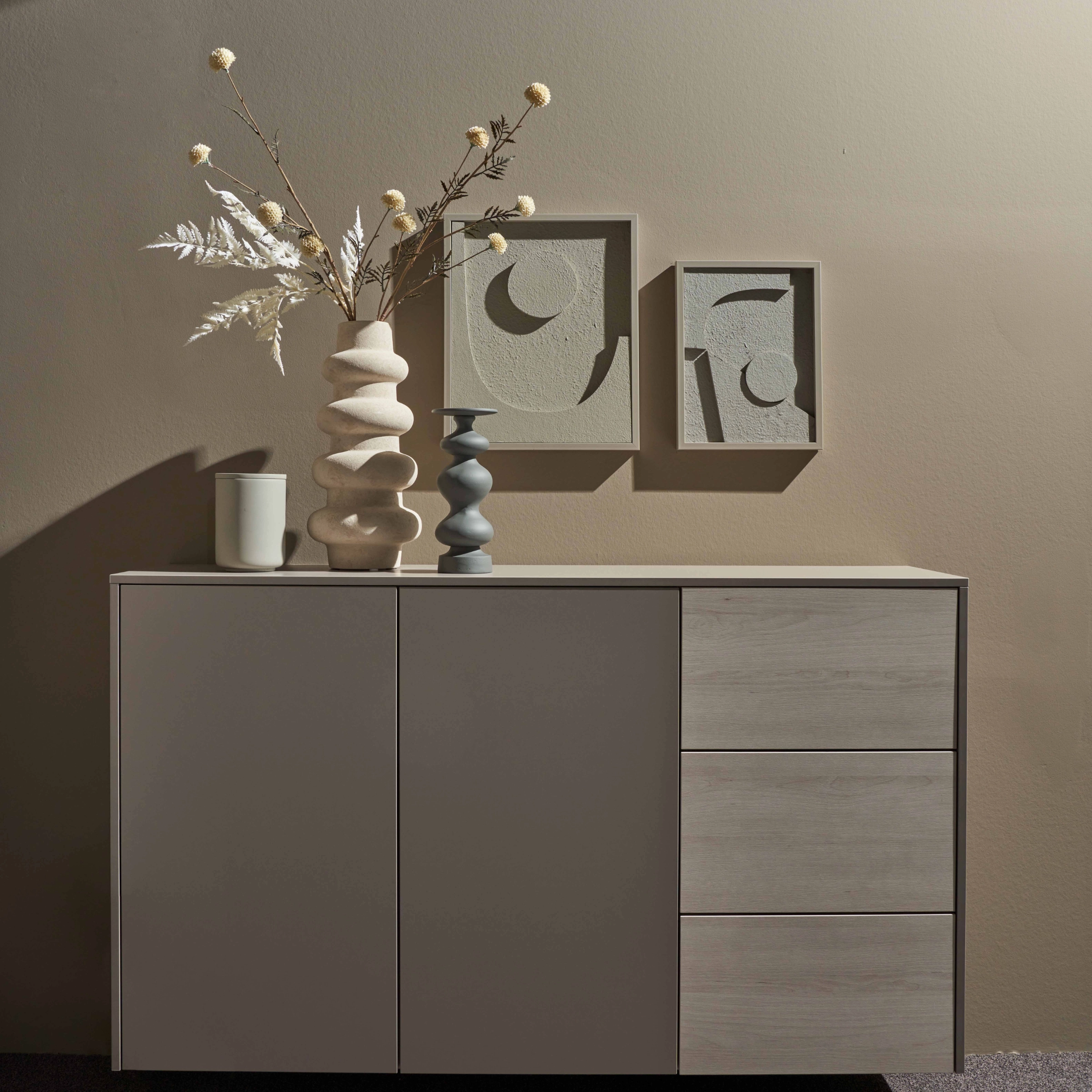 Un buffet avec des vases décoratifs et des œuvres d'art au mur, Nolte Living.