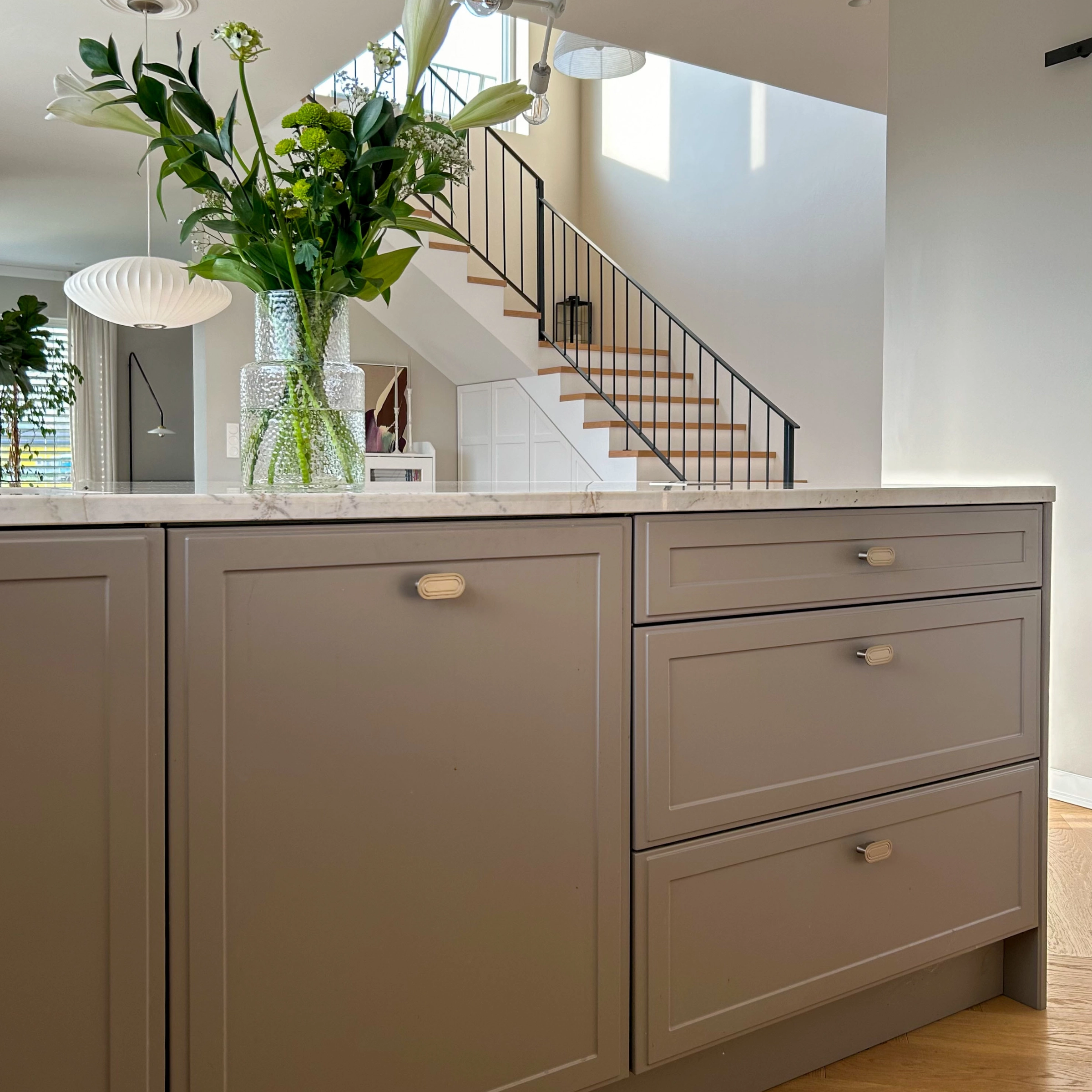 Dans une cuisine moderne avec des fleurs sur le plan de travail, le design de Nolte Kitchen est mis en valeur.