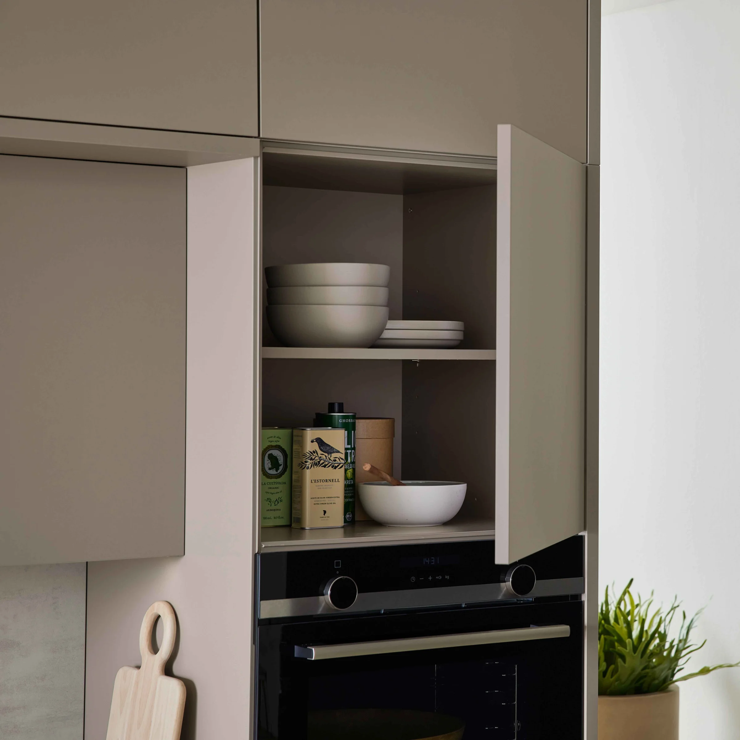 Open kasten in de keuken met kommen en een plant. Nolte Küchen.