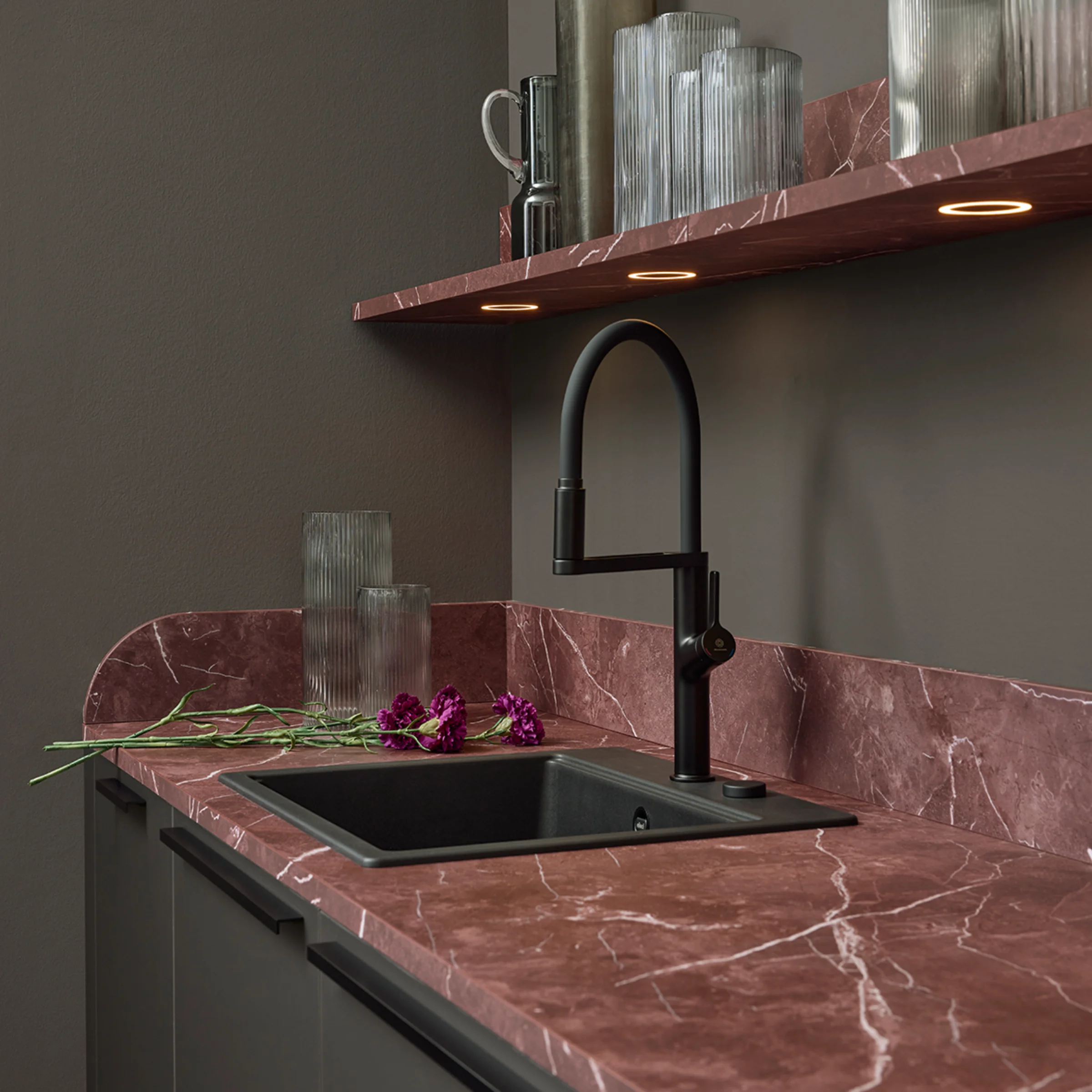 Eine stilvolle Küche mit roten Marmorarbeitsflächen und modernen Regalen. Nolte Küchen.