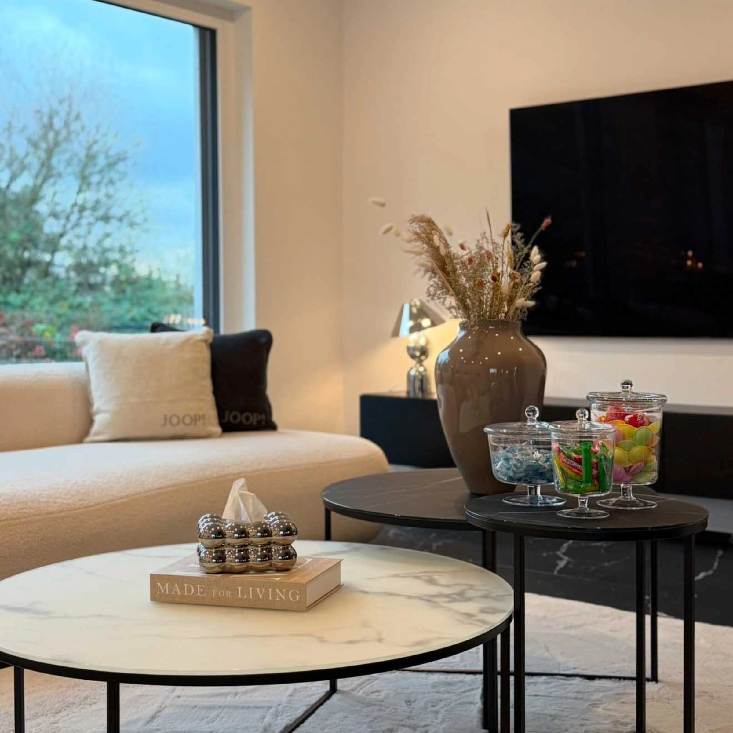 Un salon élégant avec tables basses et décorations, présenté par Nolte Living.