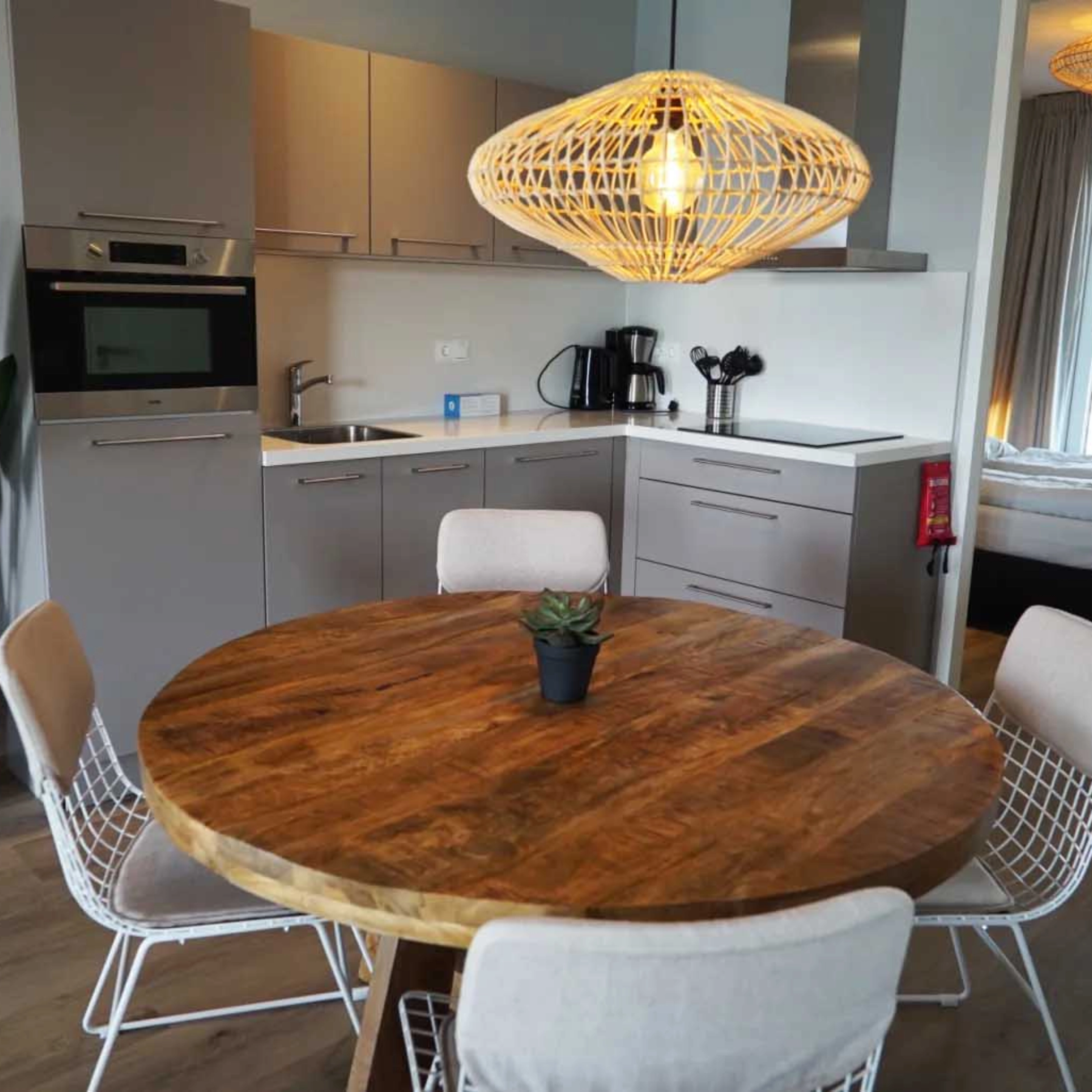 Eine moderne Küche mit rundem Holztisch und Hängelampe, im Hintergrund Nolte Küchen.