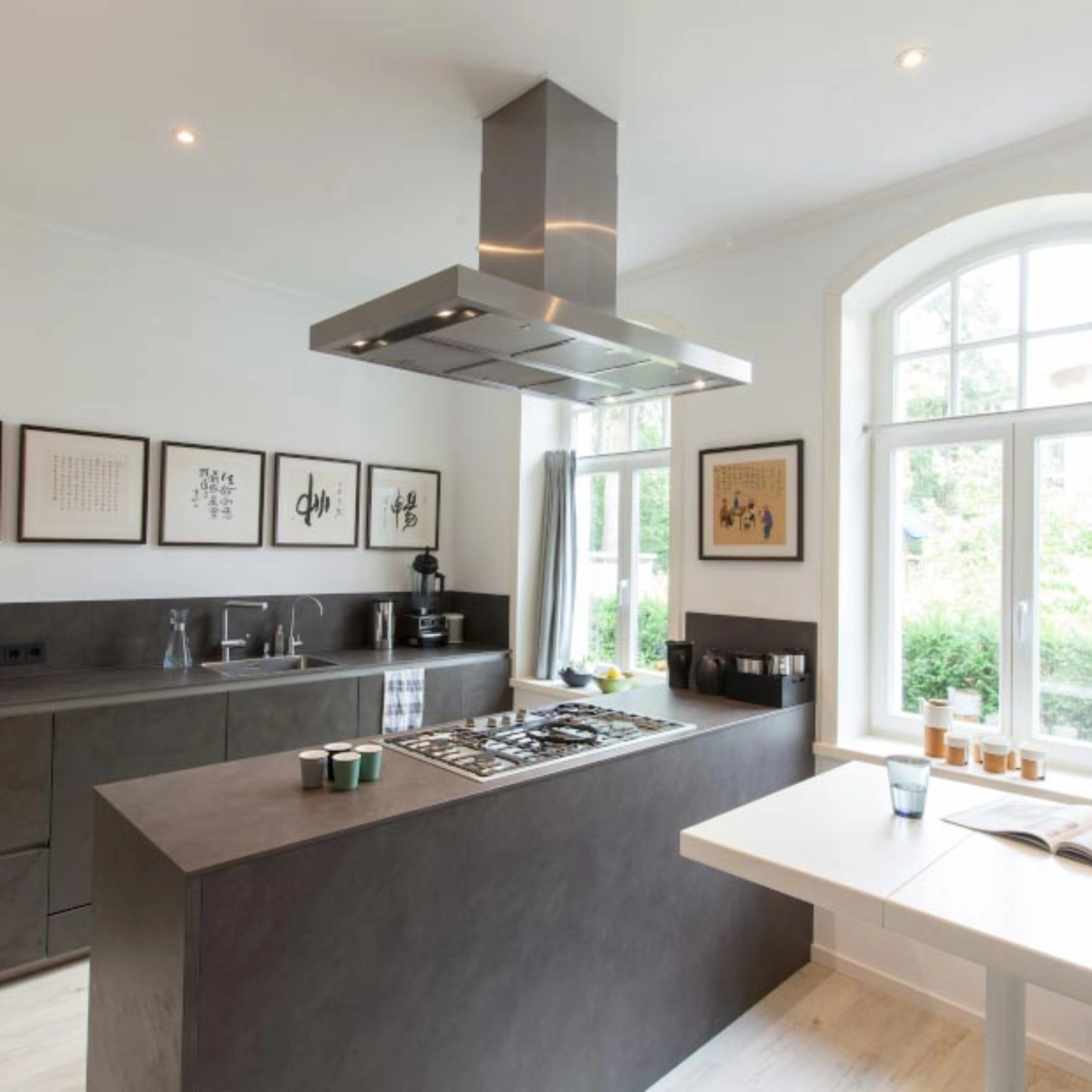 Cuisine moderne avec armoires sombres et îlot central dans une pièce lumineuse. Nolte Kitchen.